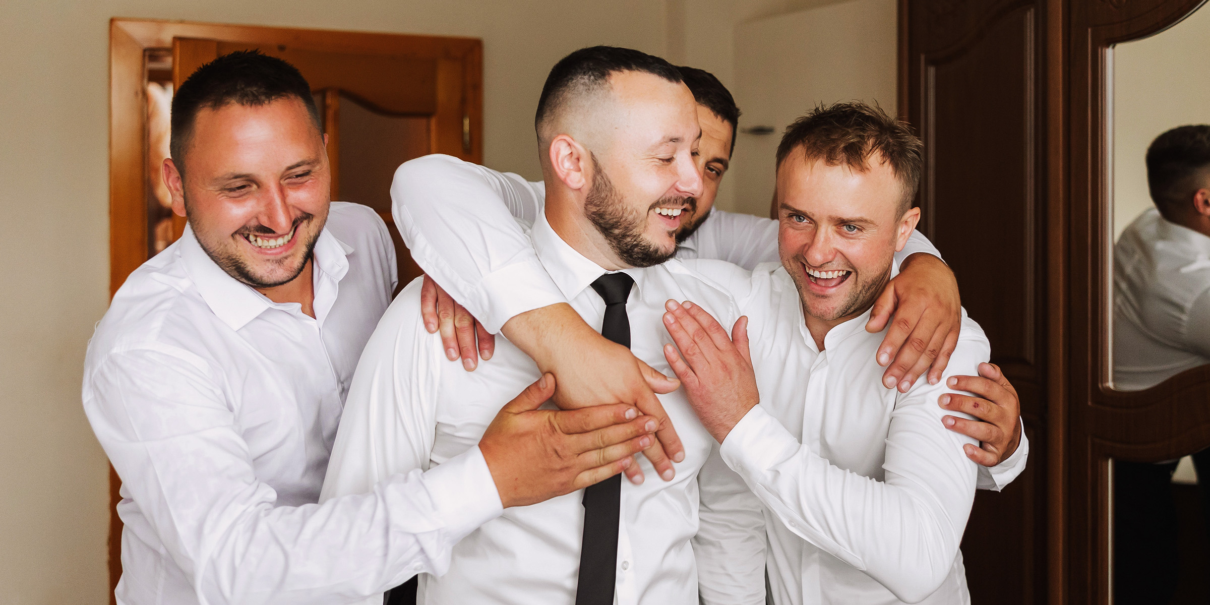 Ein Bräutigam lacht mit seinen Trauzeugen | Quelle: Shutterstock