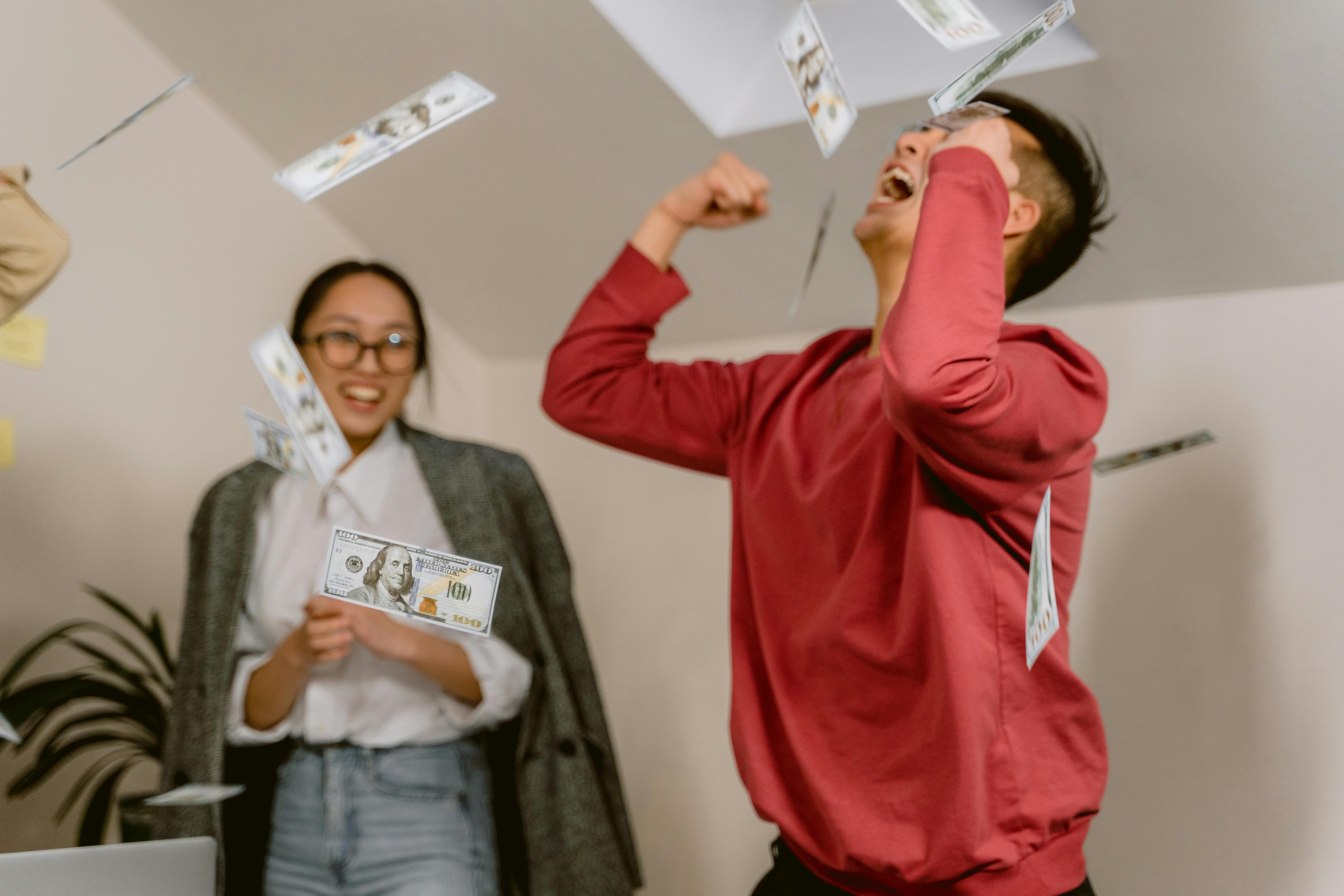 Eine Frau sieht einem Mann zu, der feiert, indem er Geld in die Luft wirft | Quelle: Pexels