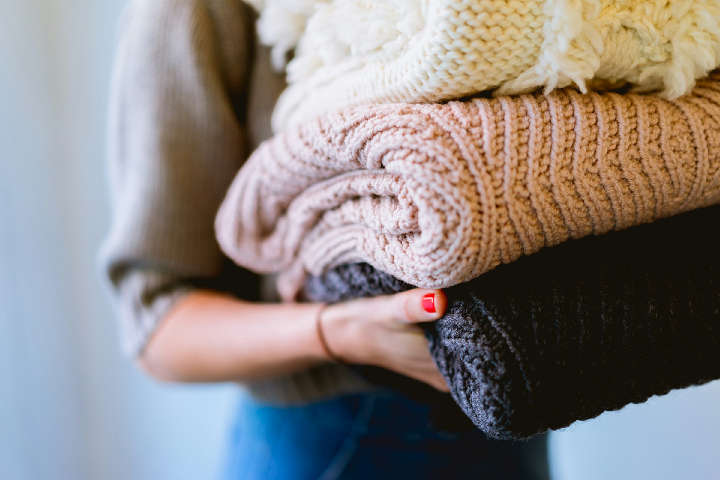 Frau trägt einen Stapel Wollkleidung | Quelle: Unsplash