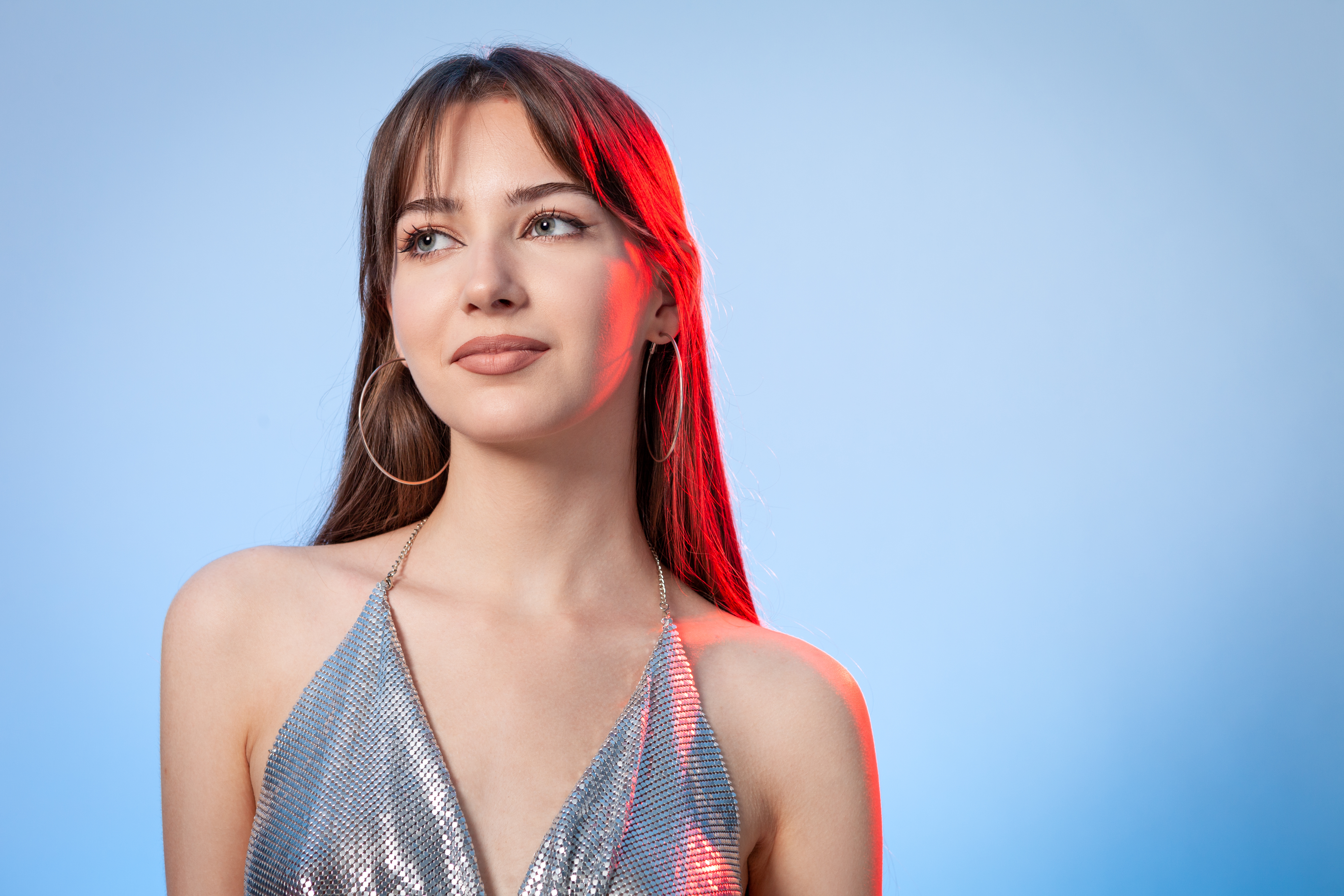 Studio-Porträt einer schönen jungen weißen Frau mit langen braunen Haaren vor einem blauen Hintergrund | Quelle: Getty Images