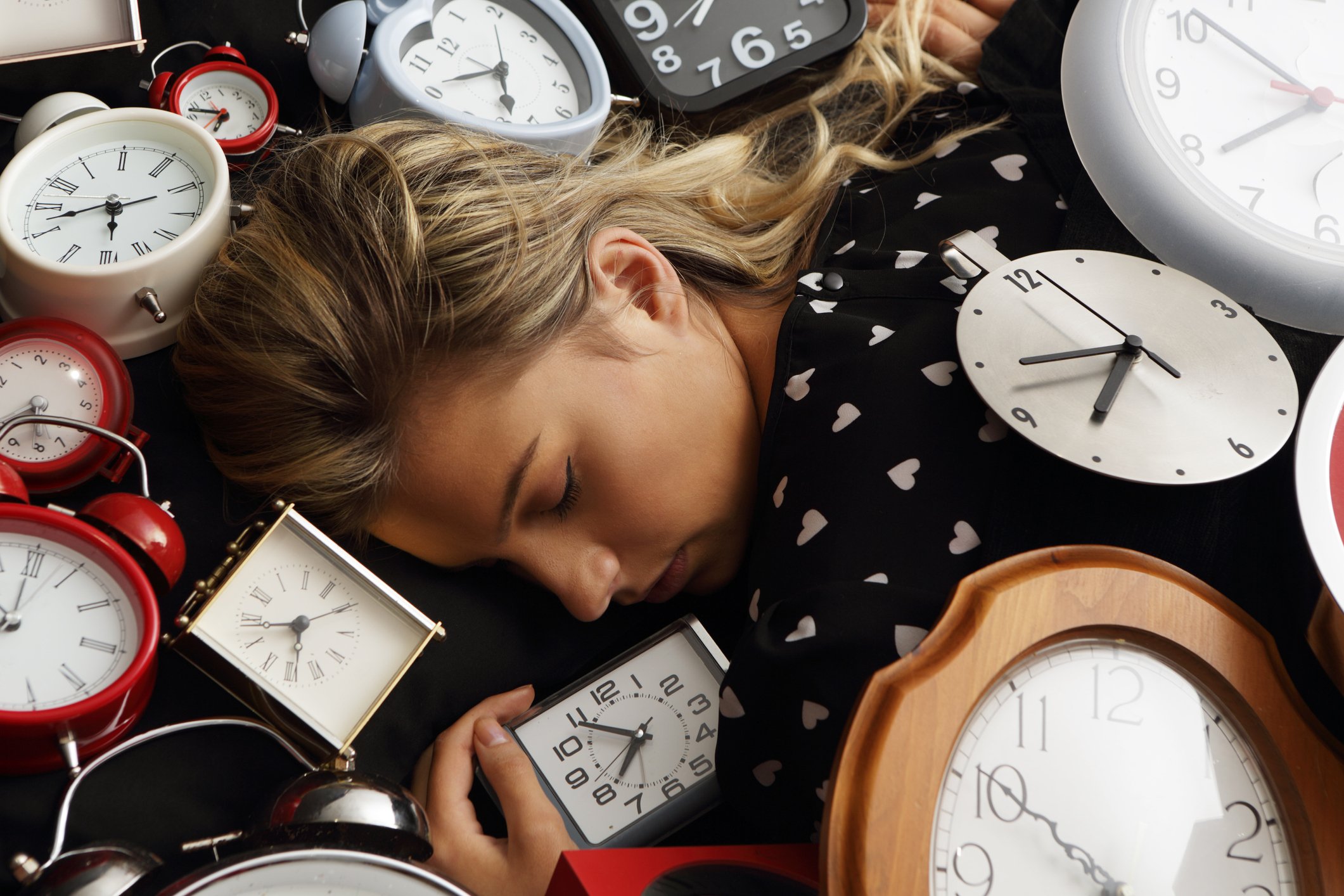 Frau schläft umgeben von Uhren. I Quelle: Getty Images
