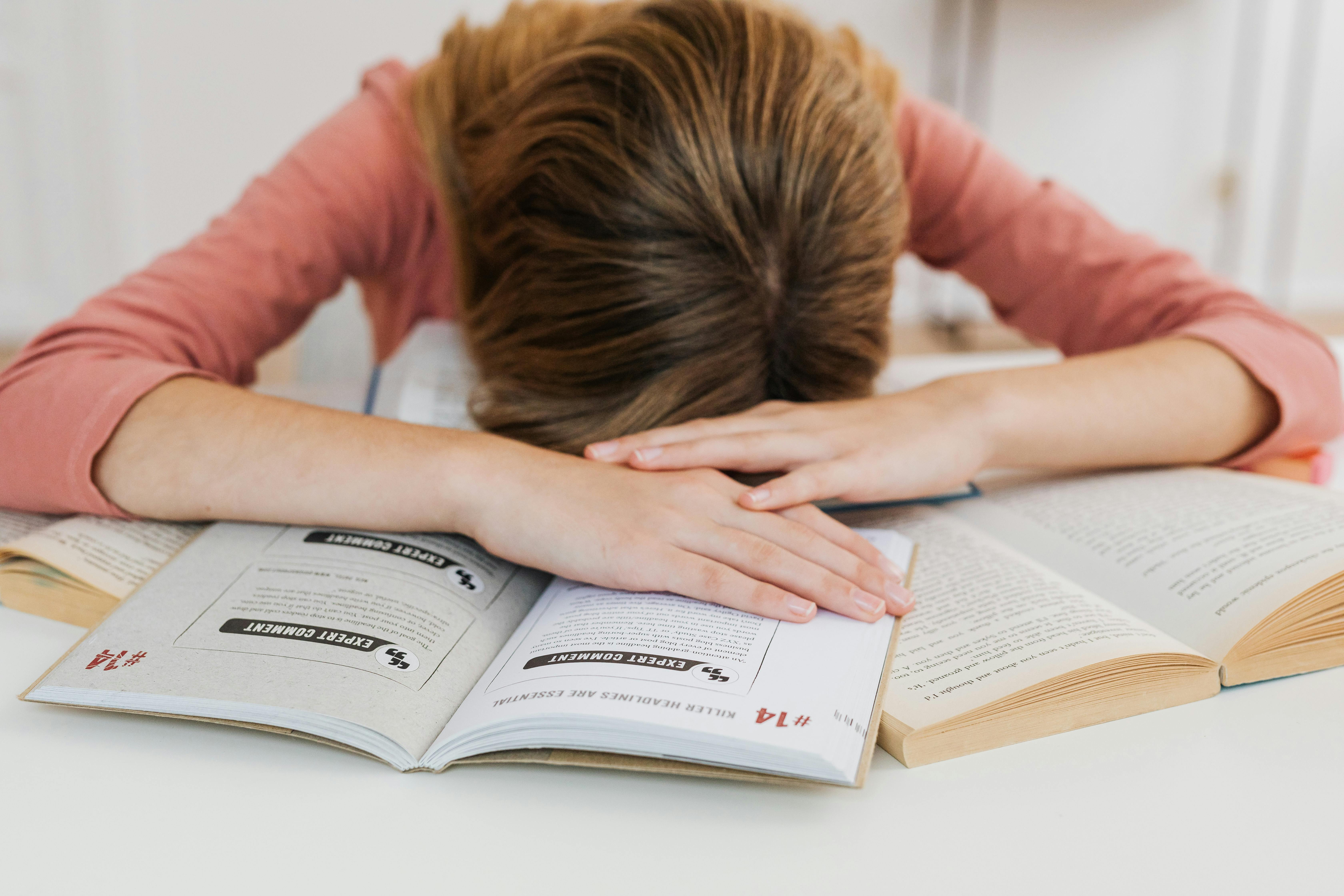Ein gestresstes Mädchen, das auf seinen Büchern liegt | Quelle: Pexels