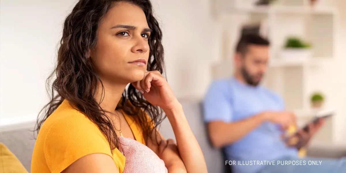 Eine ernste, in ihre Gedanken versunkene Frau, die neben ihrem Partner sitzt | Quelle: Shutterstock