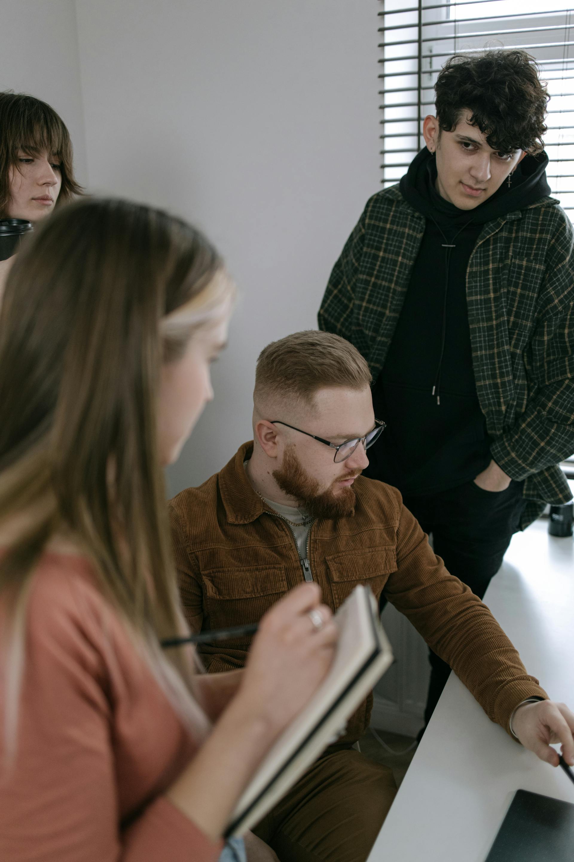 Ein junger Mann schaut seine anderen Teammitglieder während einer Diskussion über ein Gruppenprojekt an | Quelle: Pexels