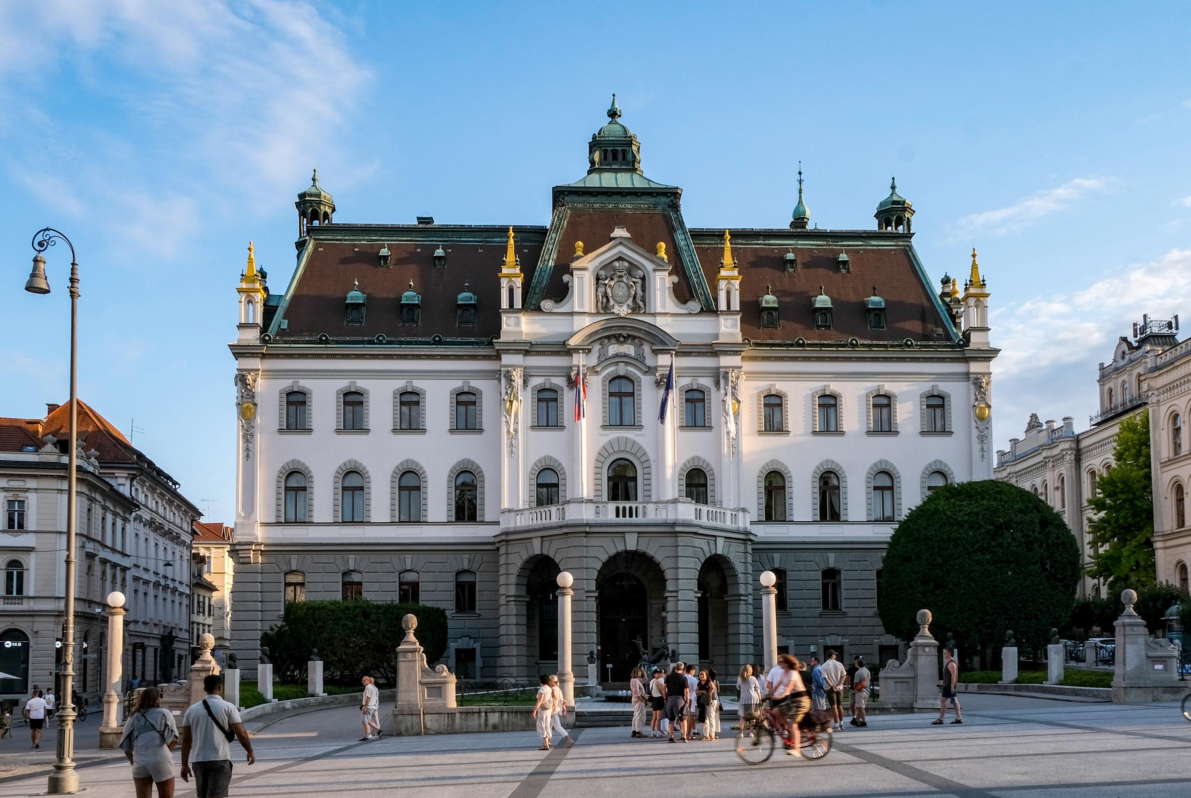 Fußgänger und Radfahrer versammeln sich am 14. Juli 2025 in Ljubljana, Slowenien, auf dem Kongressplatz vor der prunkvollen Fassade der Universität Ljubljana. Das stattliche Neorenaissance-Gebäude dient als Hauptsitz der ältesten, größten und international hochrangigen Universität des Landes. | Quelle: Getty Images