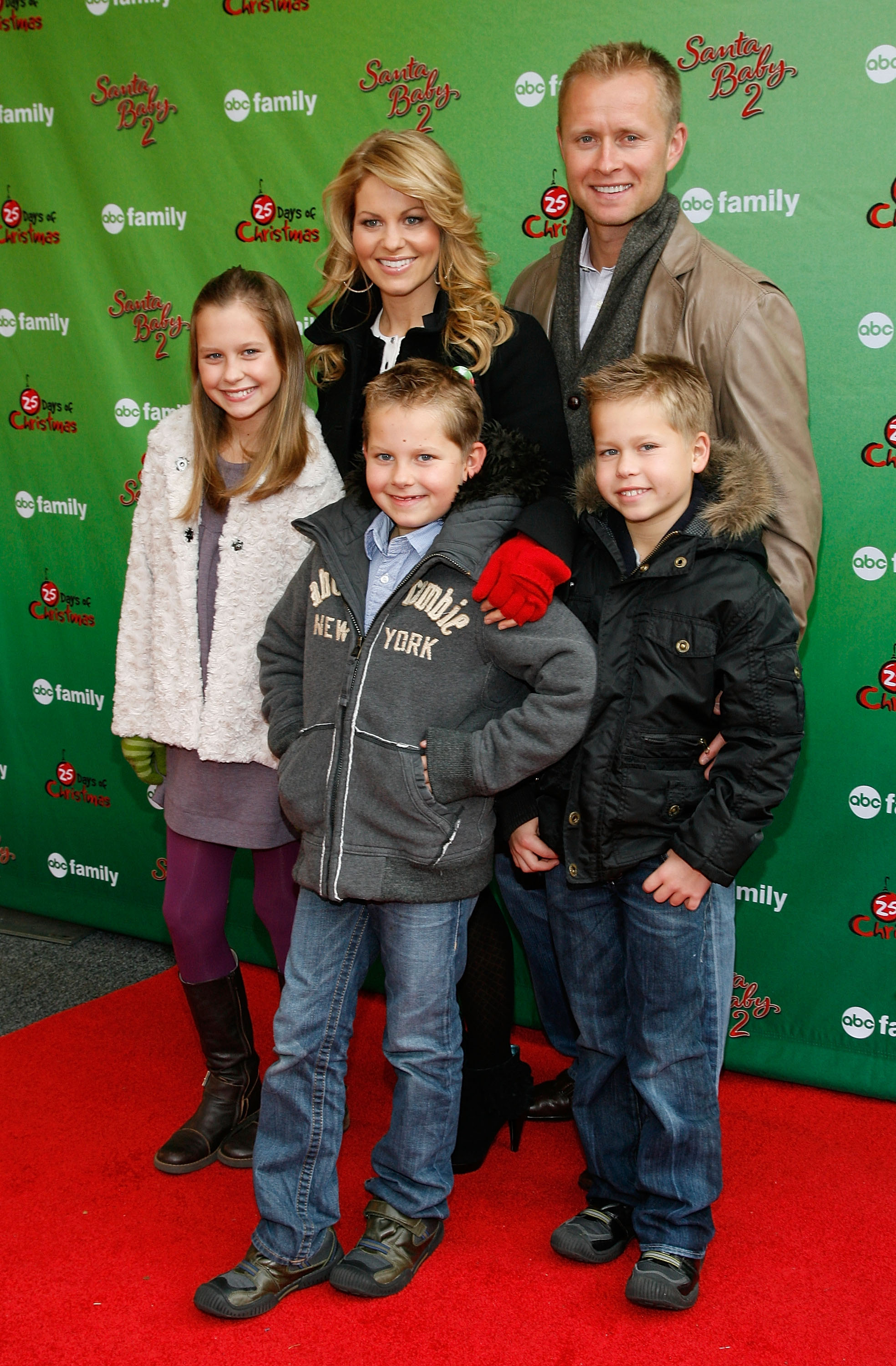 Candace Cameron Bure zeigt sich mit ihrer Familie – Ehemann Valeri Bure und den Kindern Natasha, Lev und Maksim – bei der „ABC Family World Record Elf Party“ im Bryant Park in New York City am 7. Dezember 2009. Die festlich gestimmte Gruppe hatte sich für den winterlichen roten Teppich warm angezogen: Der kleine Maksim lächelte in einem schwarzen Winterparka mit Kapuze und blauen Jeans neben seinem älteren Bruder Lev in einer grauen Fleecejacke und seiner Schwester Natasha in einer kuscheligen weißen Weste und lila Strumpfhosen. | Quelle: Getty Images