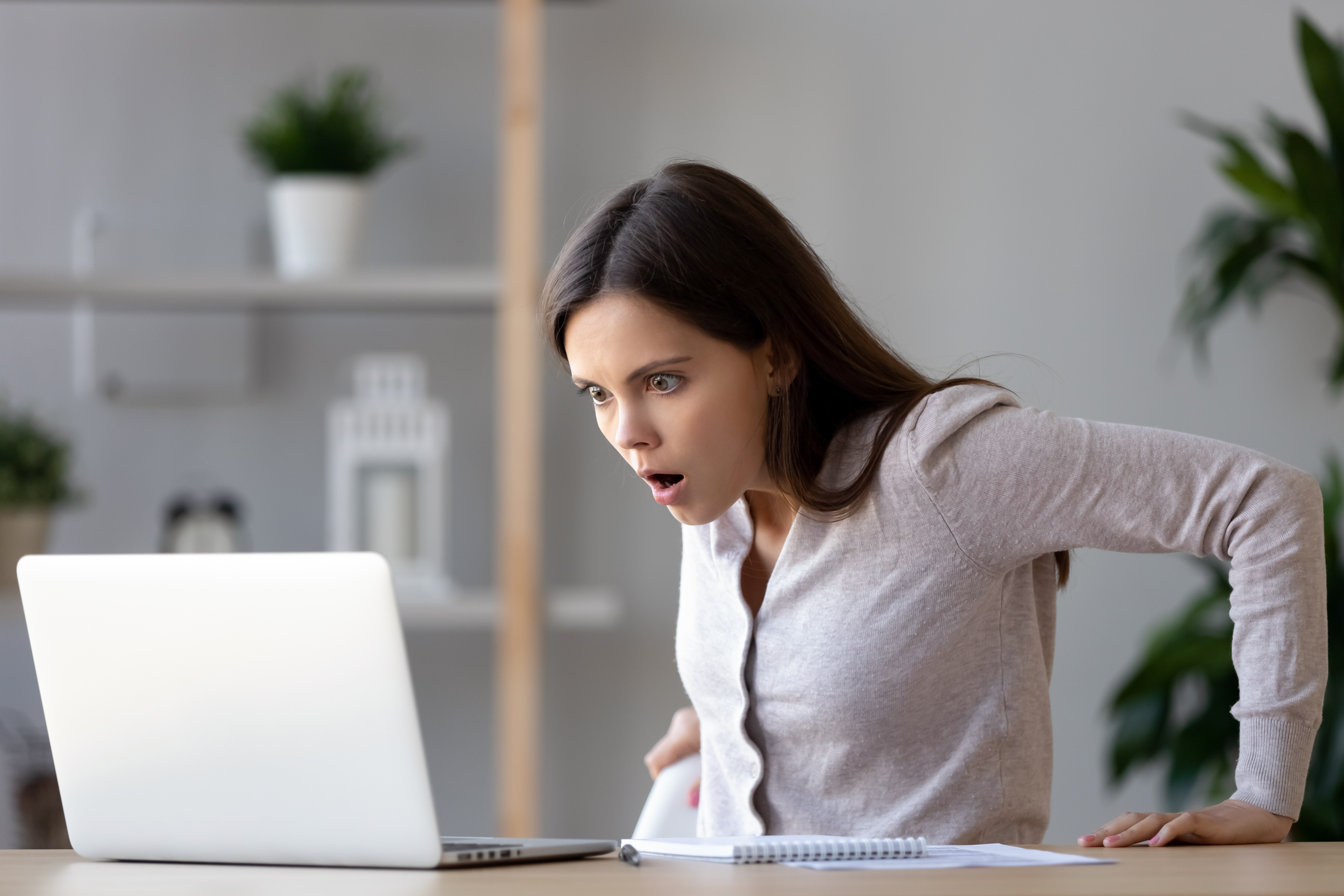 Eine junge Frau schaut schockiert auf das, was sie in einem Laptop sieht | Quelle: Shutterstock