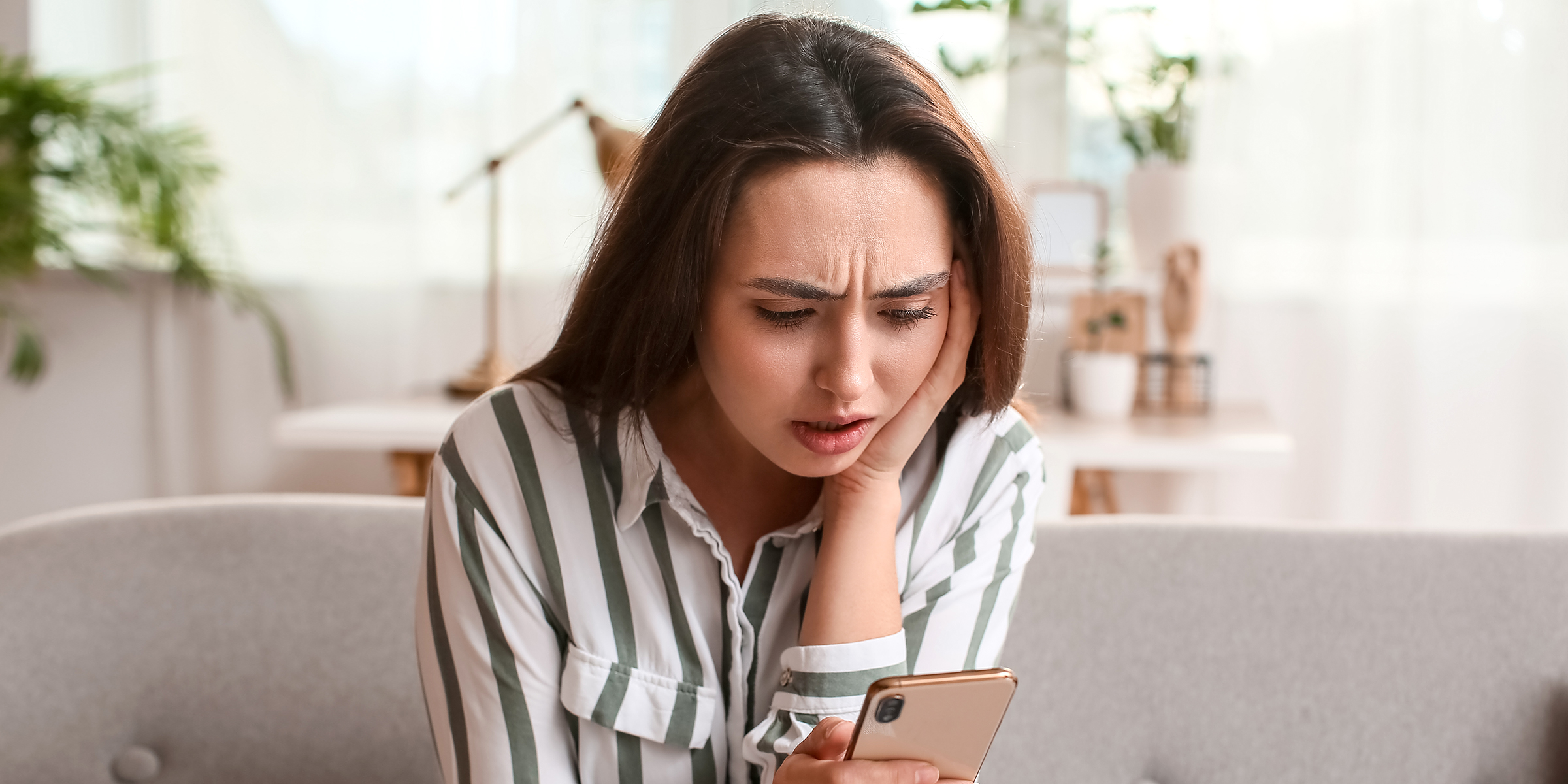 Eine geschockte Frau, die eine SMS auf ihrem Telefon liest | Quelle: Shutterstock