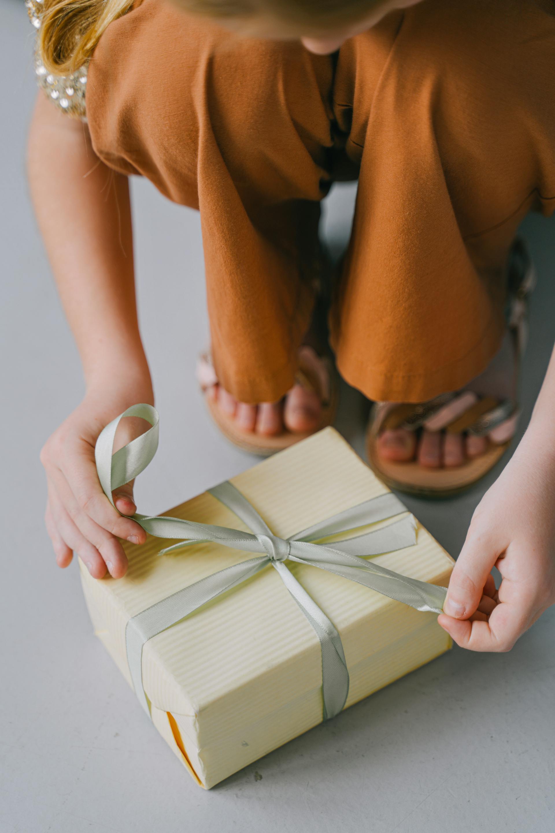 Eine Frau bindet die Schleife an einem Geschenkkarton | Quelle: Pexels