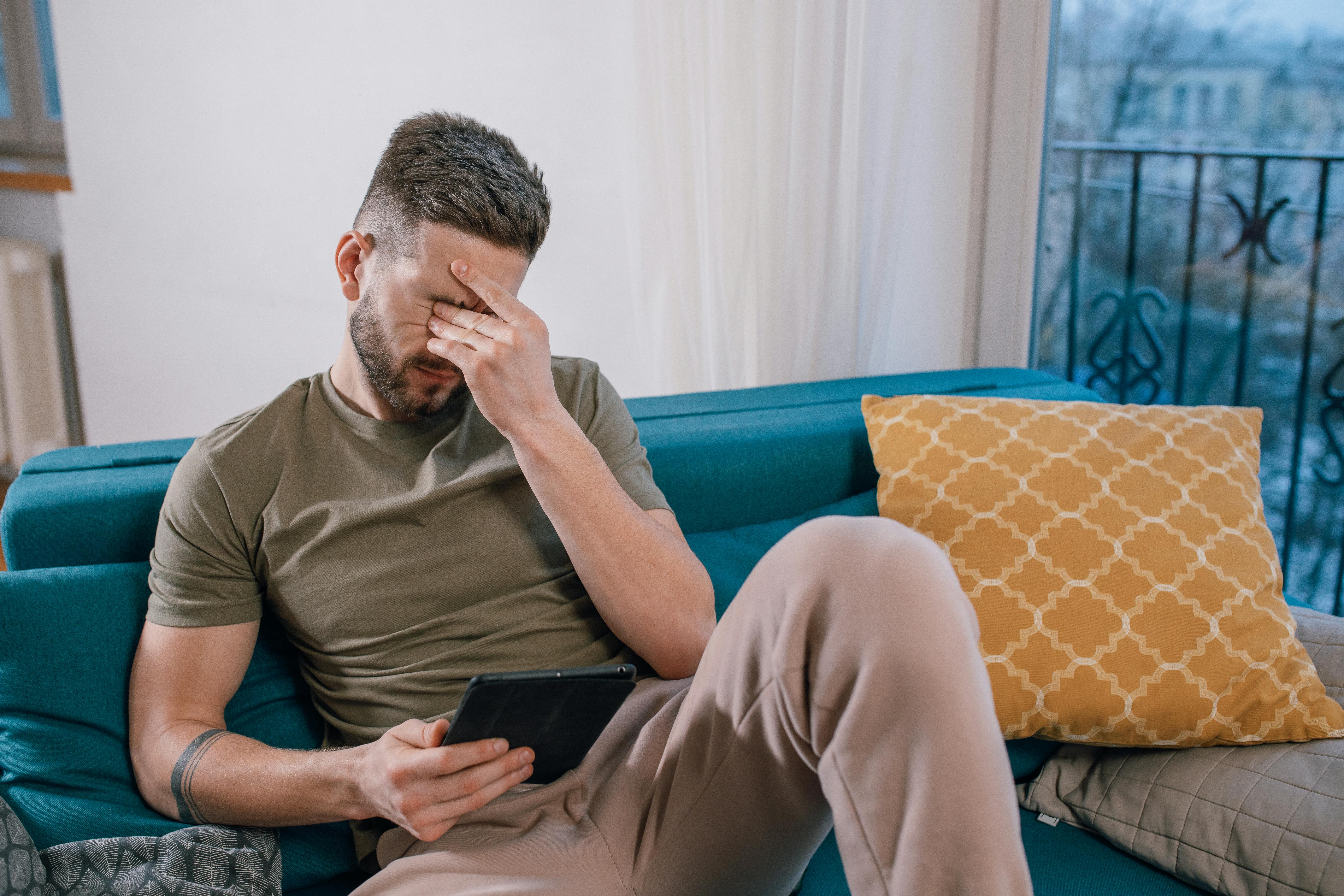 Ein Mann weint, während er an einem Tablet sitzt und etwas betrachtet | Quelle: Pexels