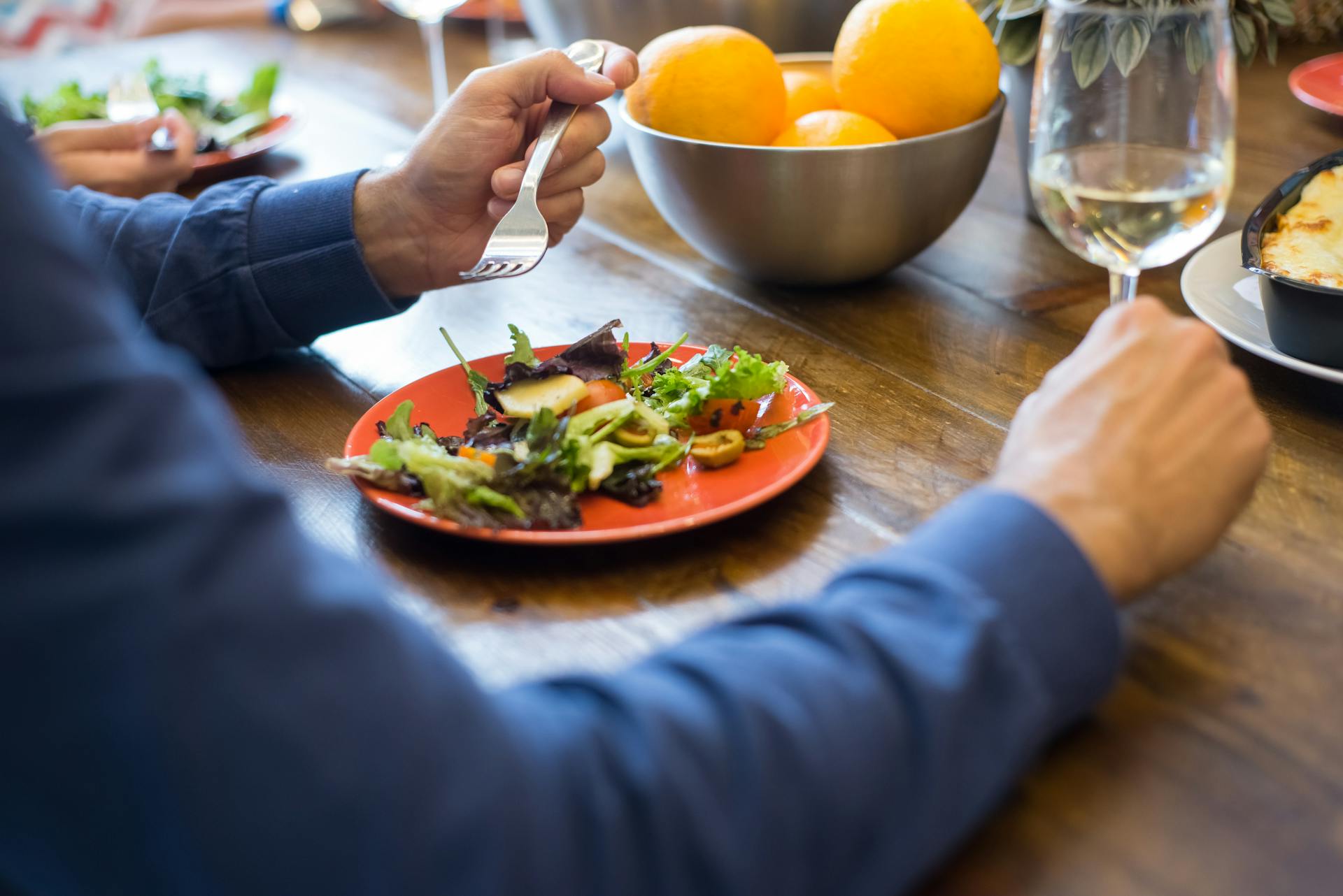 Eine Person, die an einem Tisch sitzt und Salat isst | Quelle: Pexels