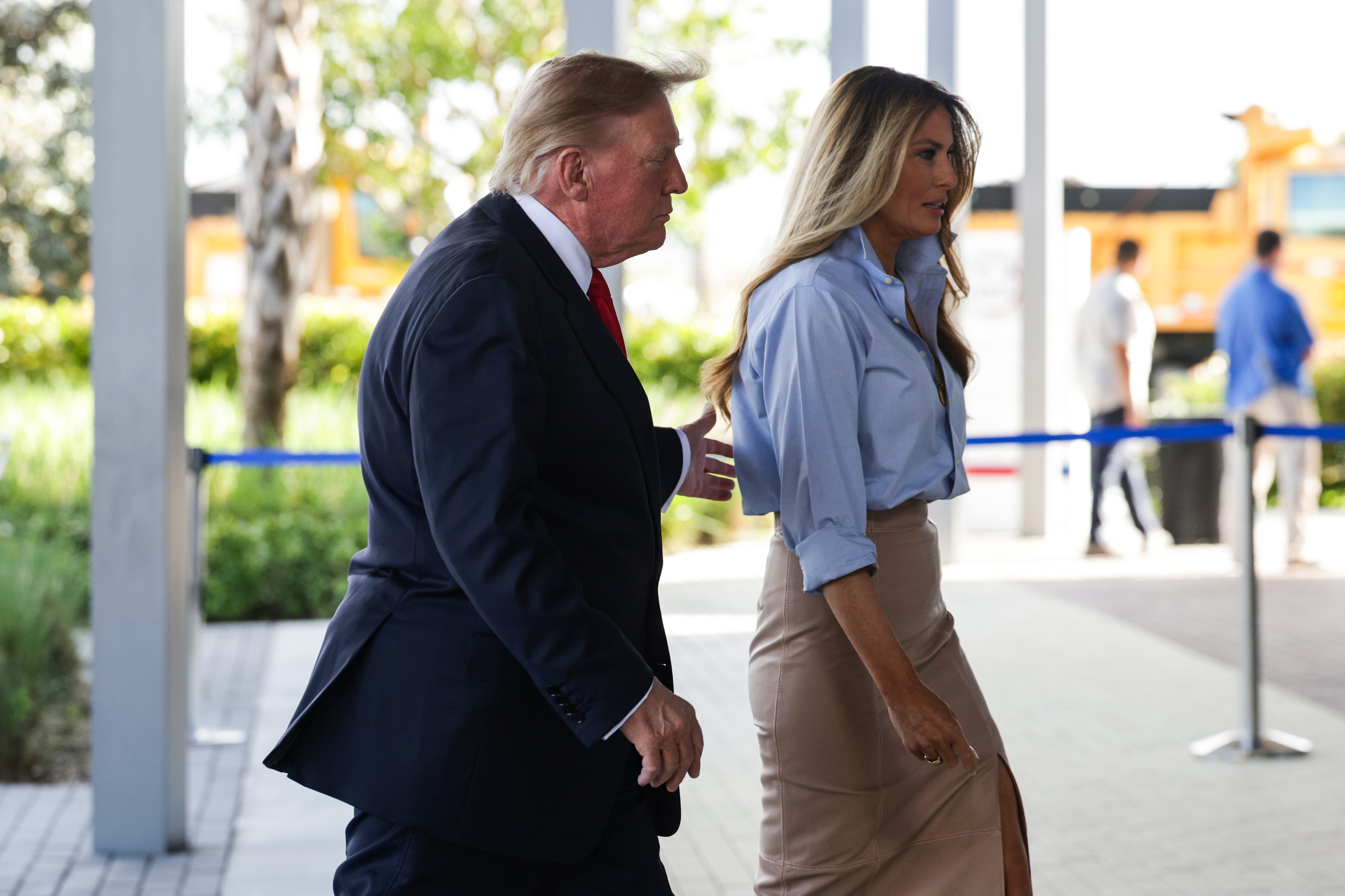 First Lady Melania Trump geht am 24. Oktober 2026 vor dem Büro des Wahlleiters von Palm Beach County in West Palm Beach, Florida, an der Seite von Präsident Donald Trump, um bei den Zwischenwahlen vorzeitig ihre Stimme abzugeben. Sie verleiht ihrer Tagesgarderobe mühelos Struktur und kombiniert ein aufgeknöpftes himmelblaues Hemd und einen hoch taillierten, beigen Bleistiftrock mit Schlitz mit hochragenden, nudefarbenen Stiletto-Pumps mit spitzer Zehenpartie, die ihren Gang elegant verlängern.