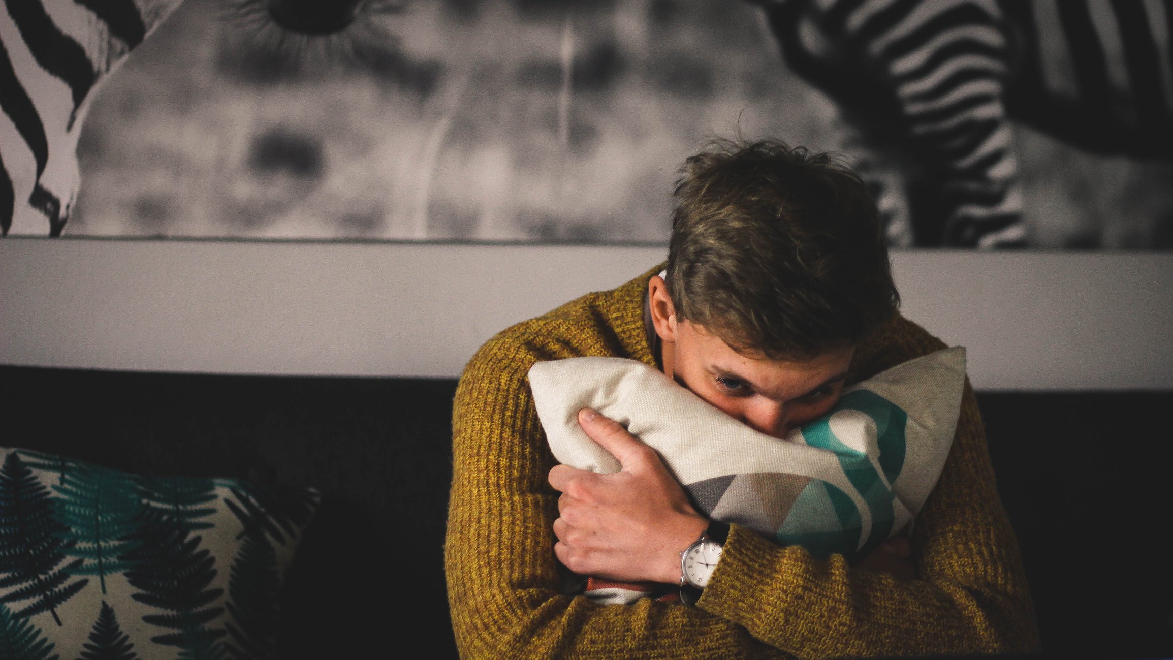 Porträt des Mannes, der ein Kissen zu Hause umarmt. I Quelle: Getty Images