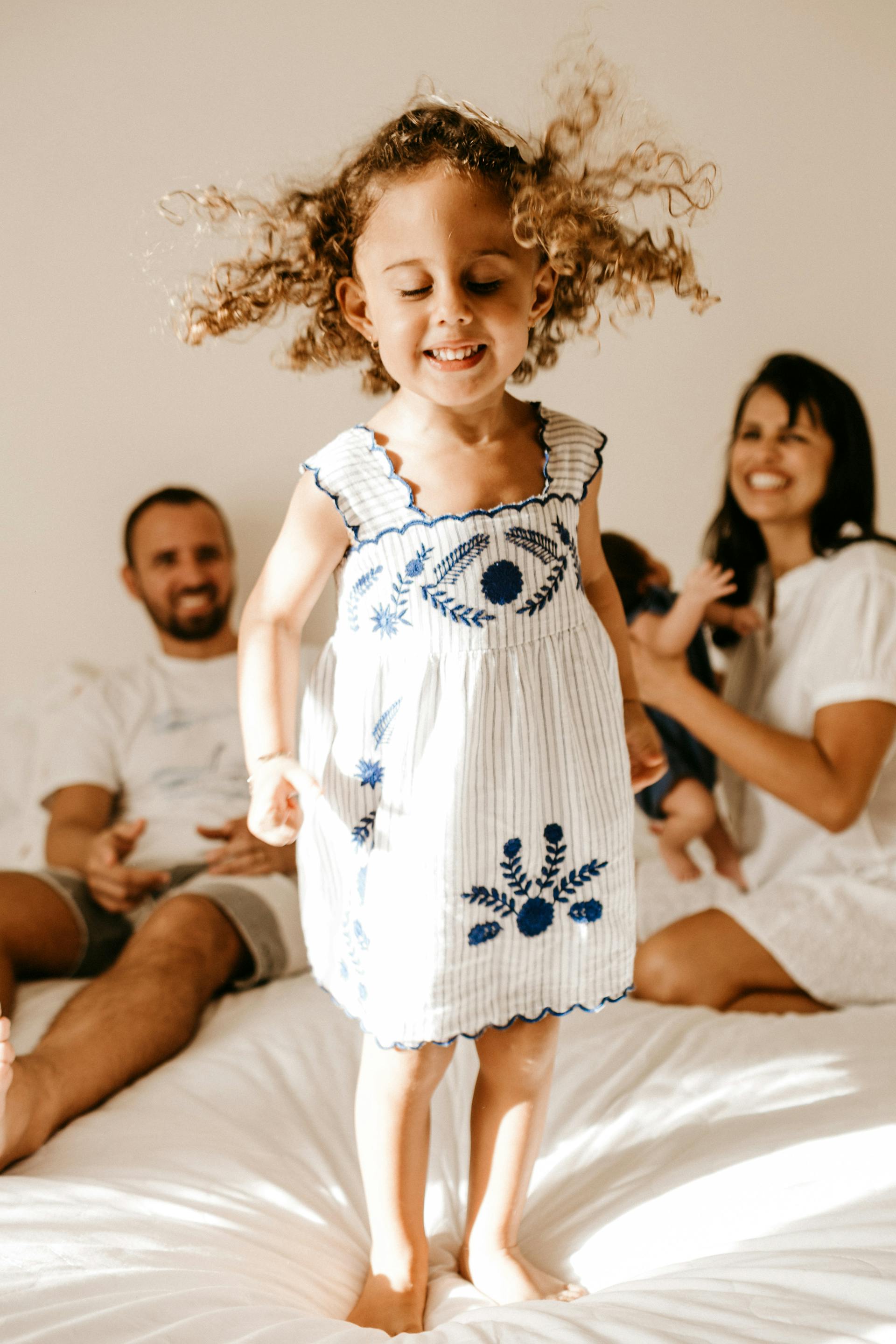 Uma menina feliz em pé em cima da cama | Fonte: Midjourney