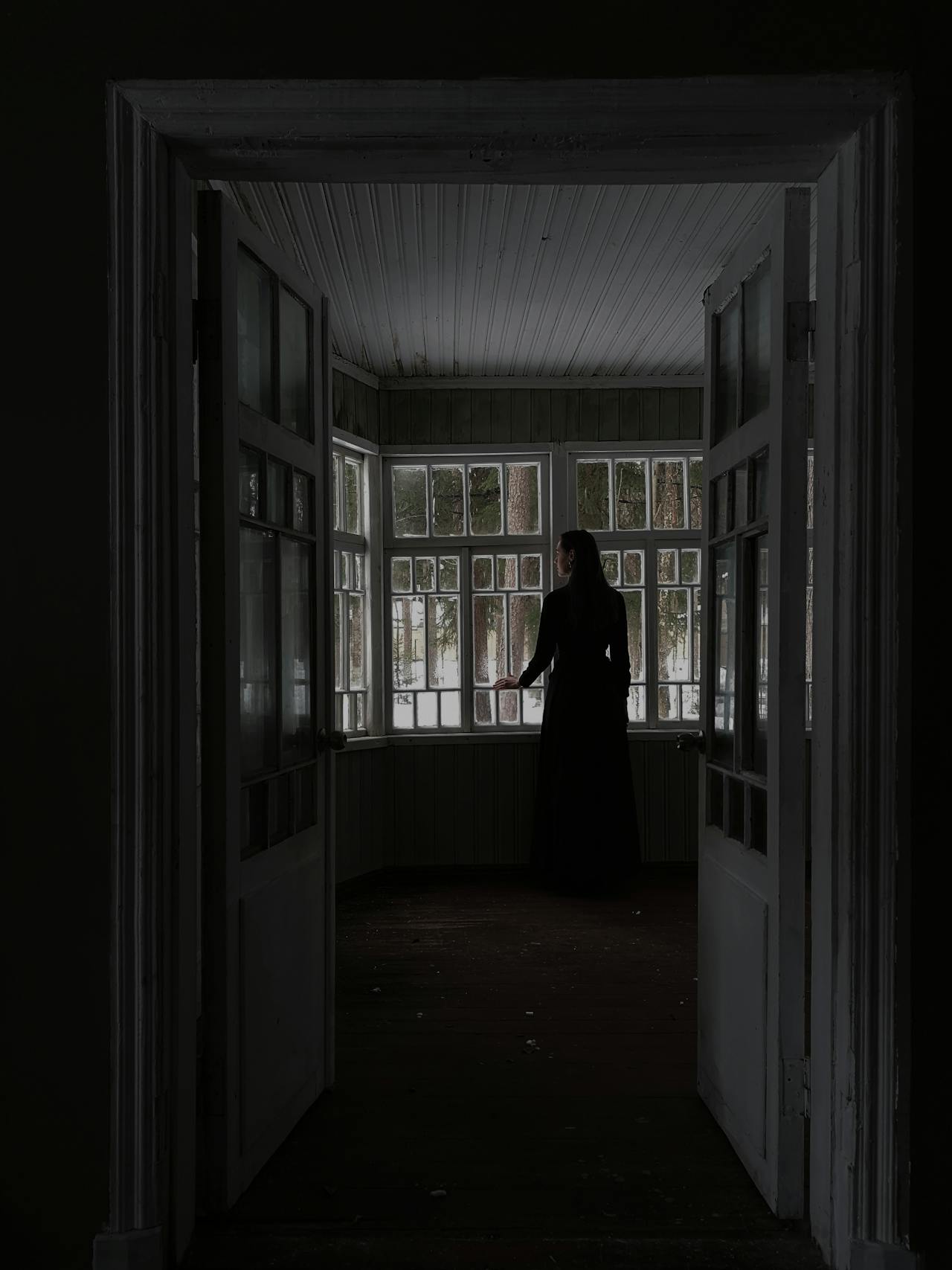 Eine einsame Frau steht am Fenster eines leeren Zimmers | Quelle: Pexels