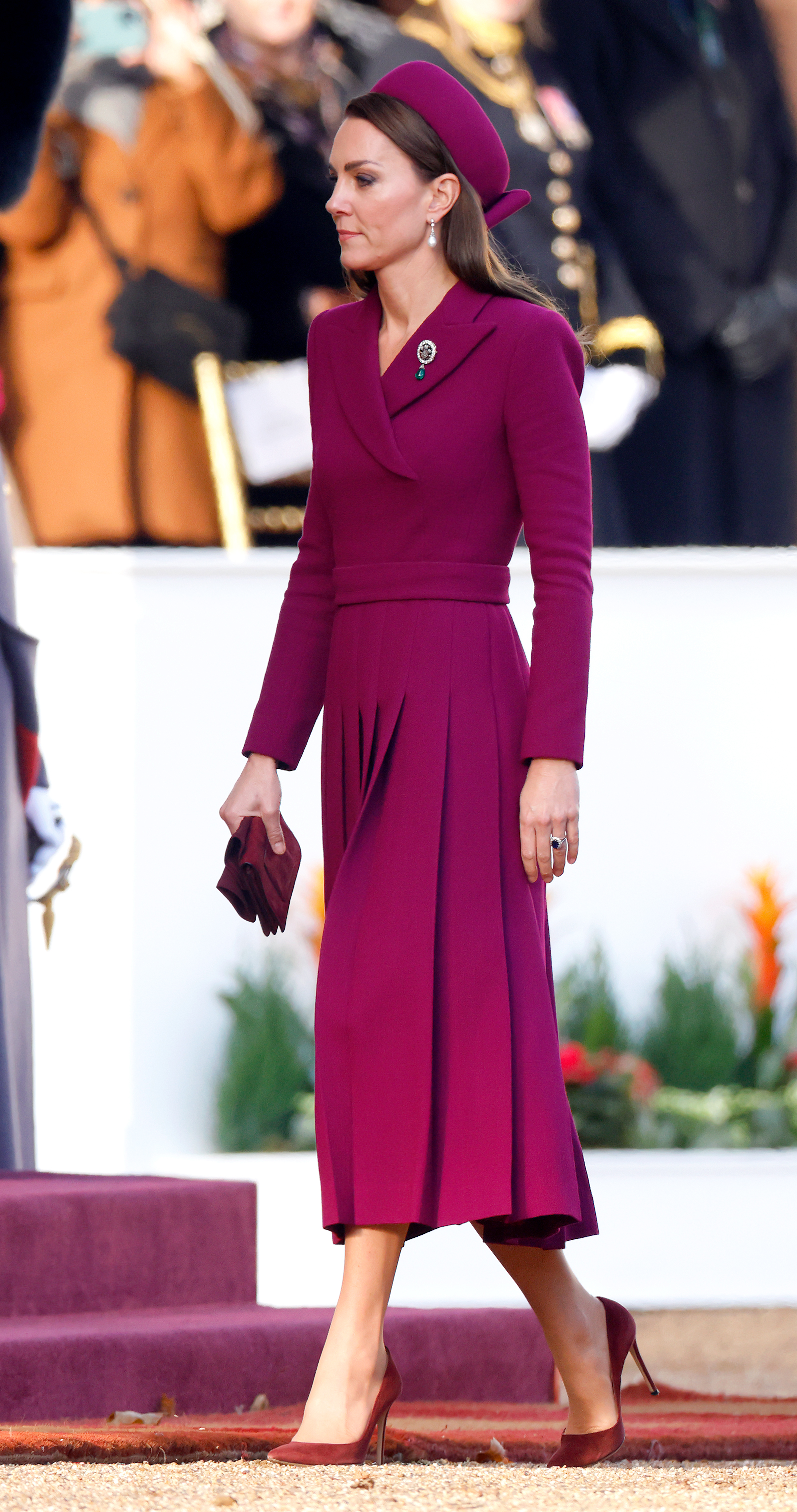 Catherine, Prinzessin von Wales, trifft am 22. November 2022 auf der Horse Guards Parade in London ein, um den südafrikanischen Präsidenten Cyril Ramaphosa im Rahmen des ersten Staatsbesuchs unter der Regentschaft von König Charles III. feierlich zu empfangen. Ganz in Magenta gekleidet trägt sie ein maßgeschneidertes Mantelkleid von Emilia Wickstead mit asymmetrischem Kragen, Gürtel in der Taille und plissiertem Rock, dazu einen passenden Pillbox-Hut von Sean Barrett, burgunderrote Wildleder-Pumps und Handschuhe, Prinzessin Dianas Perlen-Ohrringe sowie die „Queen Alexandra Three Feathers“-Brosche, die an ihrem Revers befestigt ist. | Quelle: Getty Images