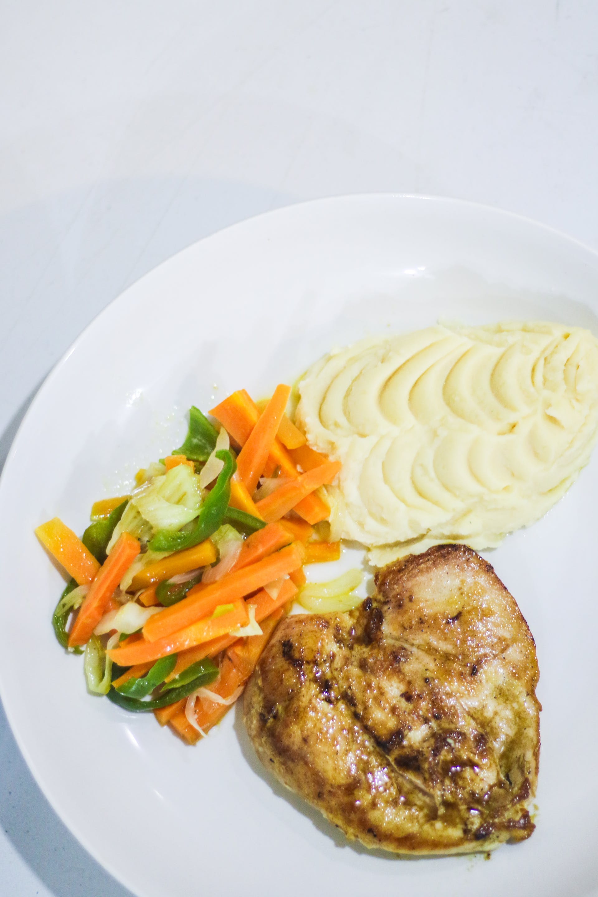 Ein Teller mit Hähnchenbrust, Gemüse und Kartoffelpüree | Quelle: Pexels