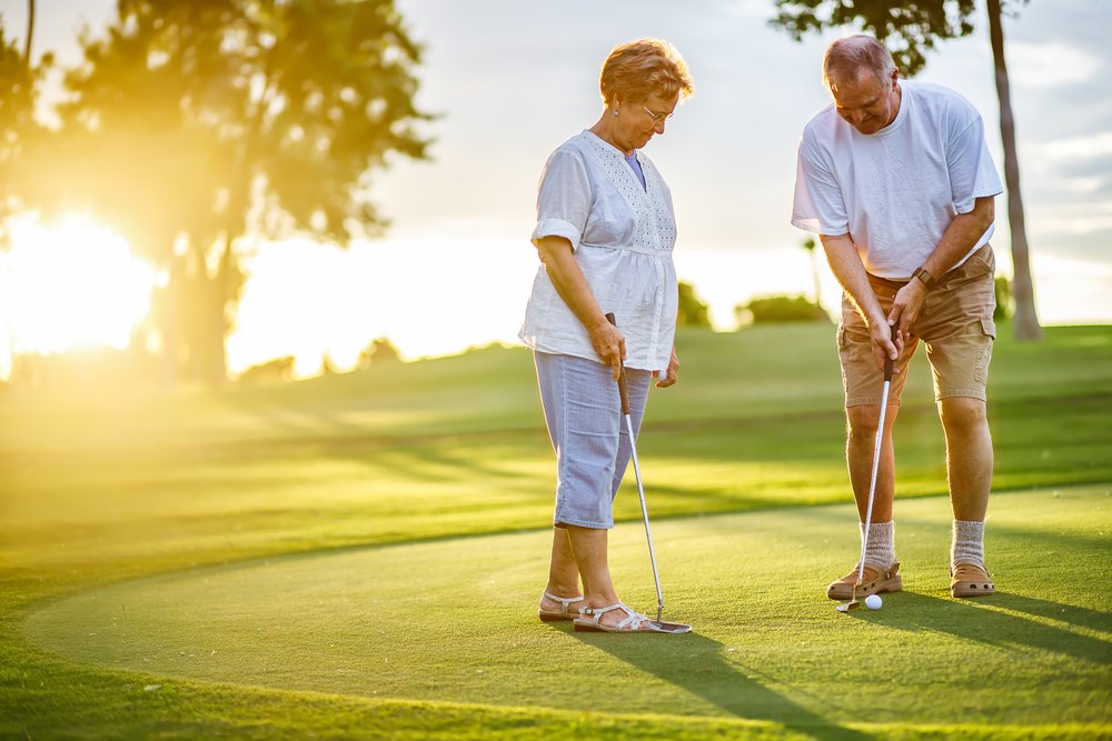 Älteres Ehepaar, das bei Sonnenuntergang zusammen Golf spielt | Quelle: Shutterstock