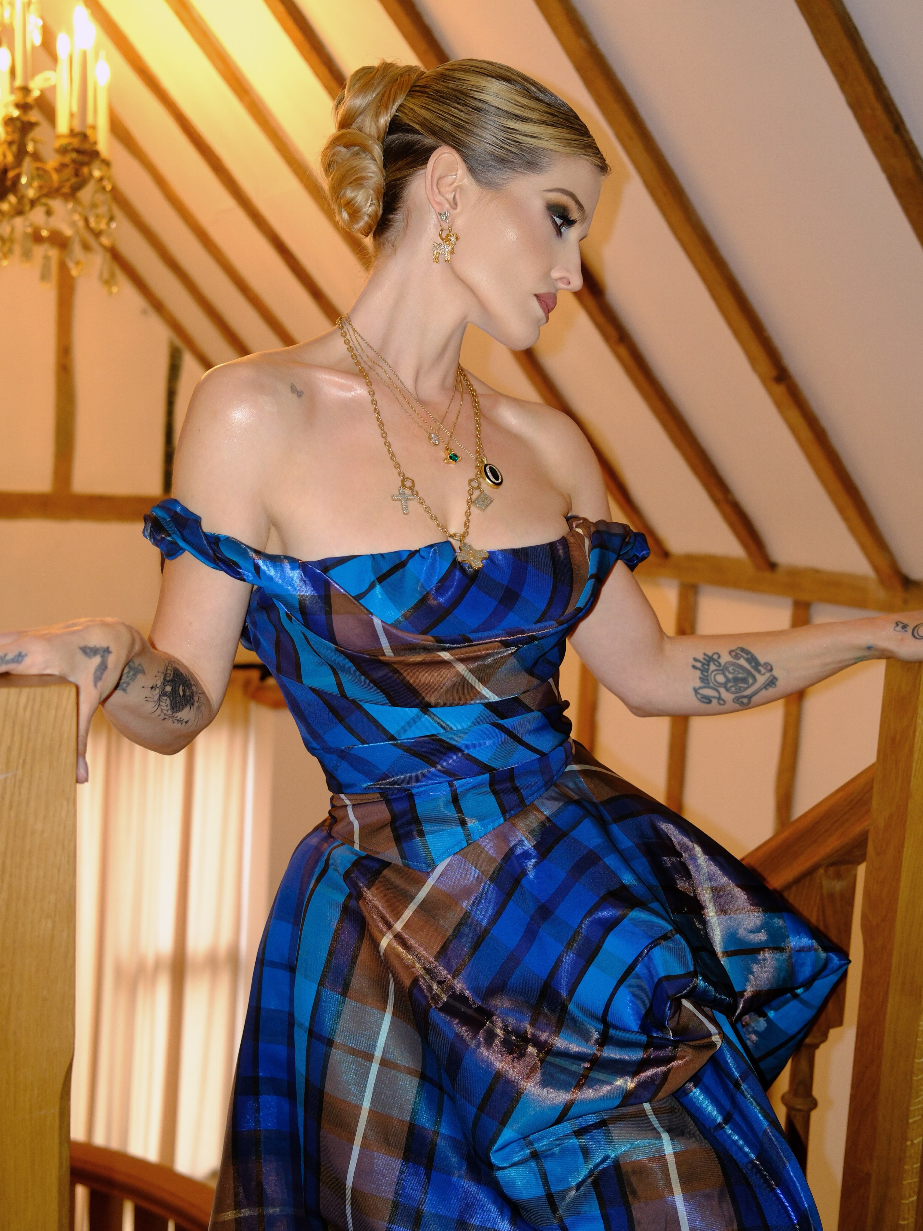 Kelly nimmt auf einer Holztreppe eine dramatische Pose ein und präsentiert dabei die asymmetrische Silhouette und den voluminösen Rock ihres 3.485 € teuren Tartan-Kleids von Vivienne Westwood – dabei lässt sie den Stoff für sich sprechen. | Quelle: Instagram/kellyosbourne