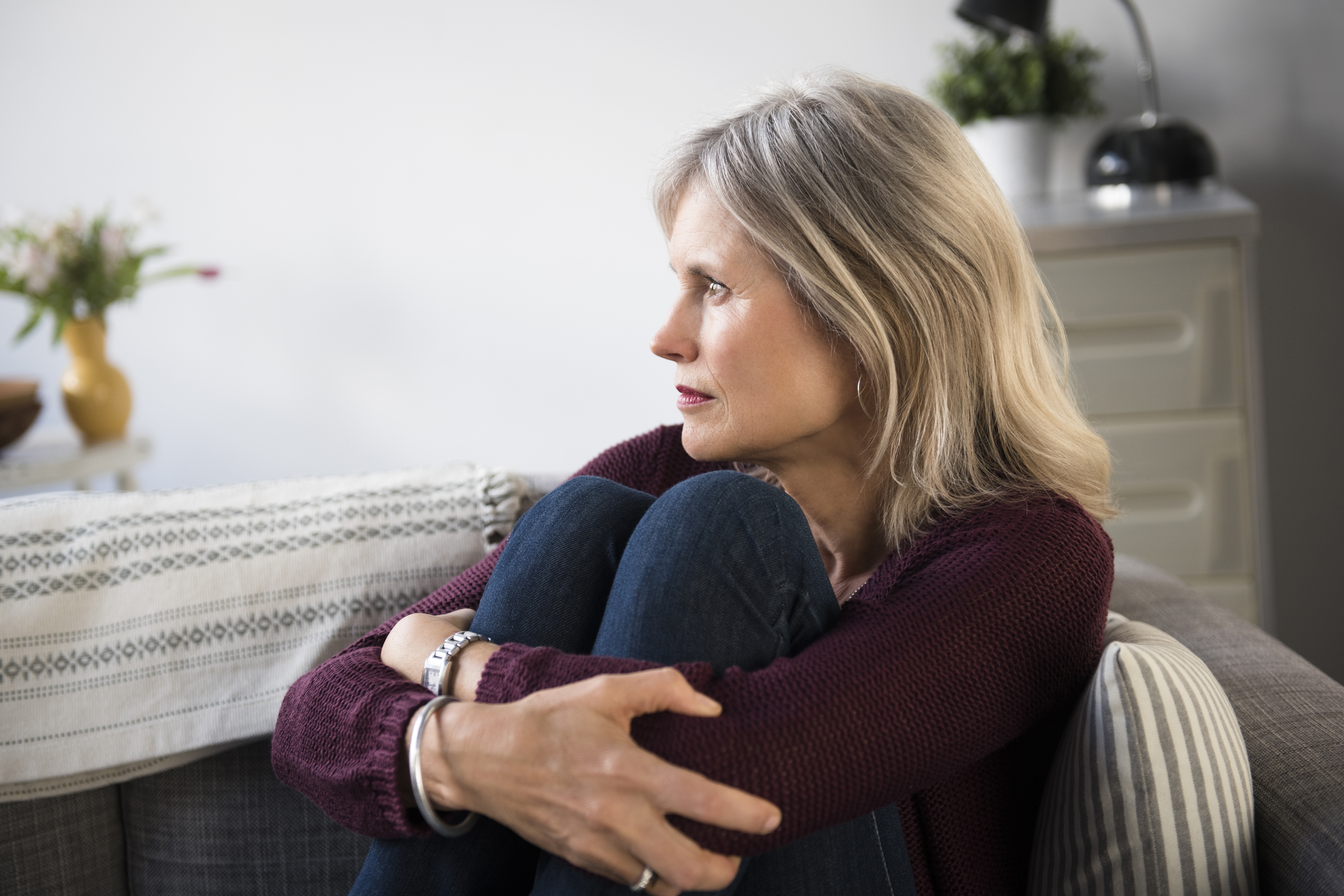 Besorgte kaukasische Frau, die ihre Beine umarmt | Quelle: Getty Images