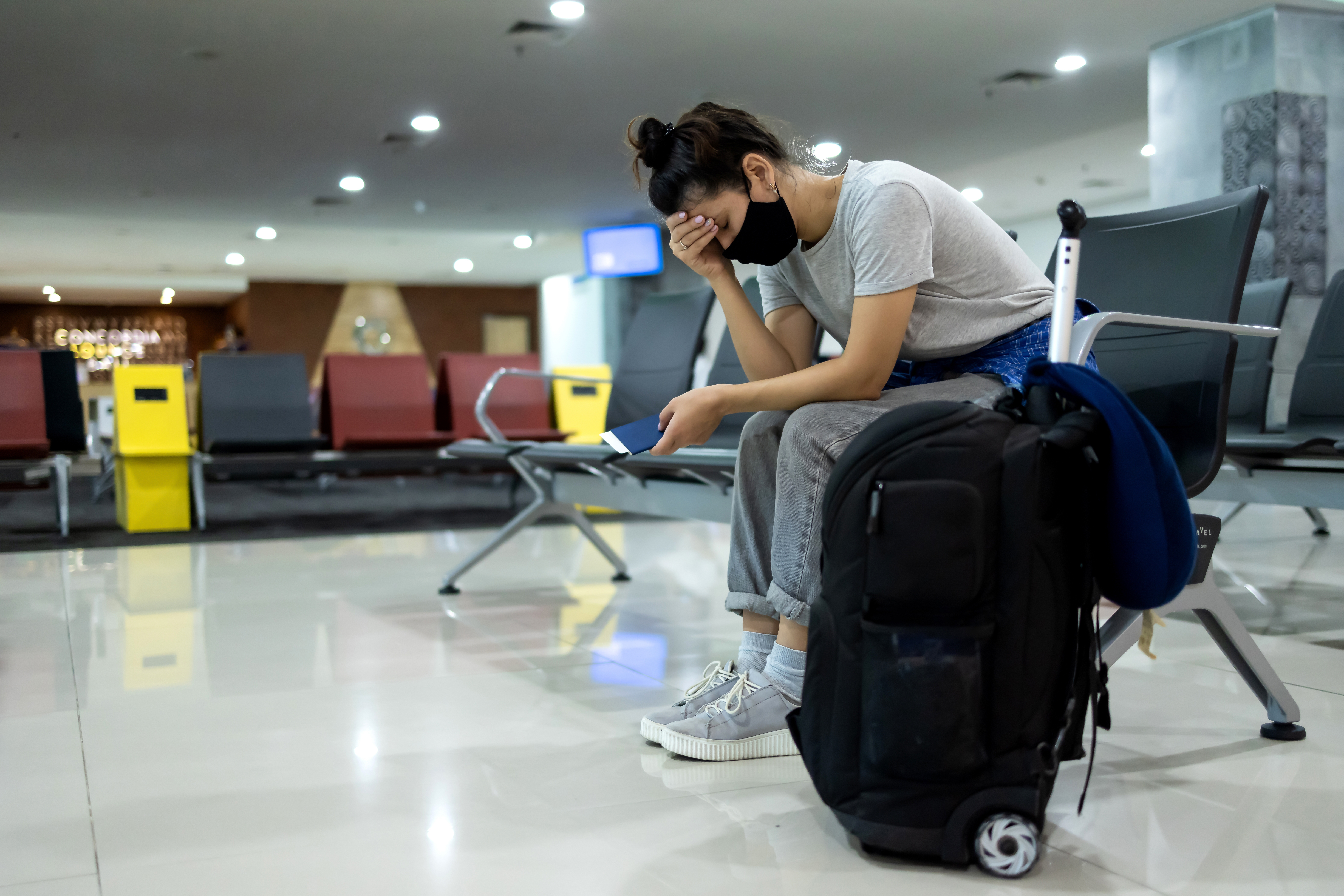 Eine Frau sitzt mit Gepäck in einer Wartehalle | Quelle: Shutterstock