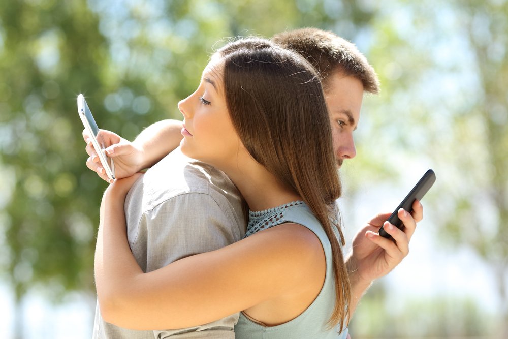 Ein Paar, dass mit anderen Partnern via Handy textet. | Quelle: Shutterstock
