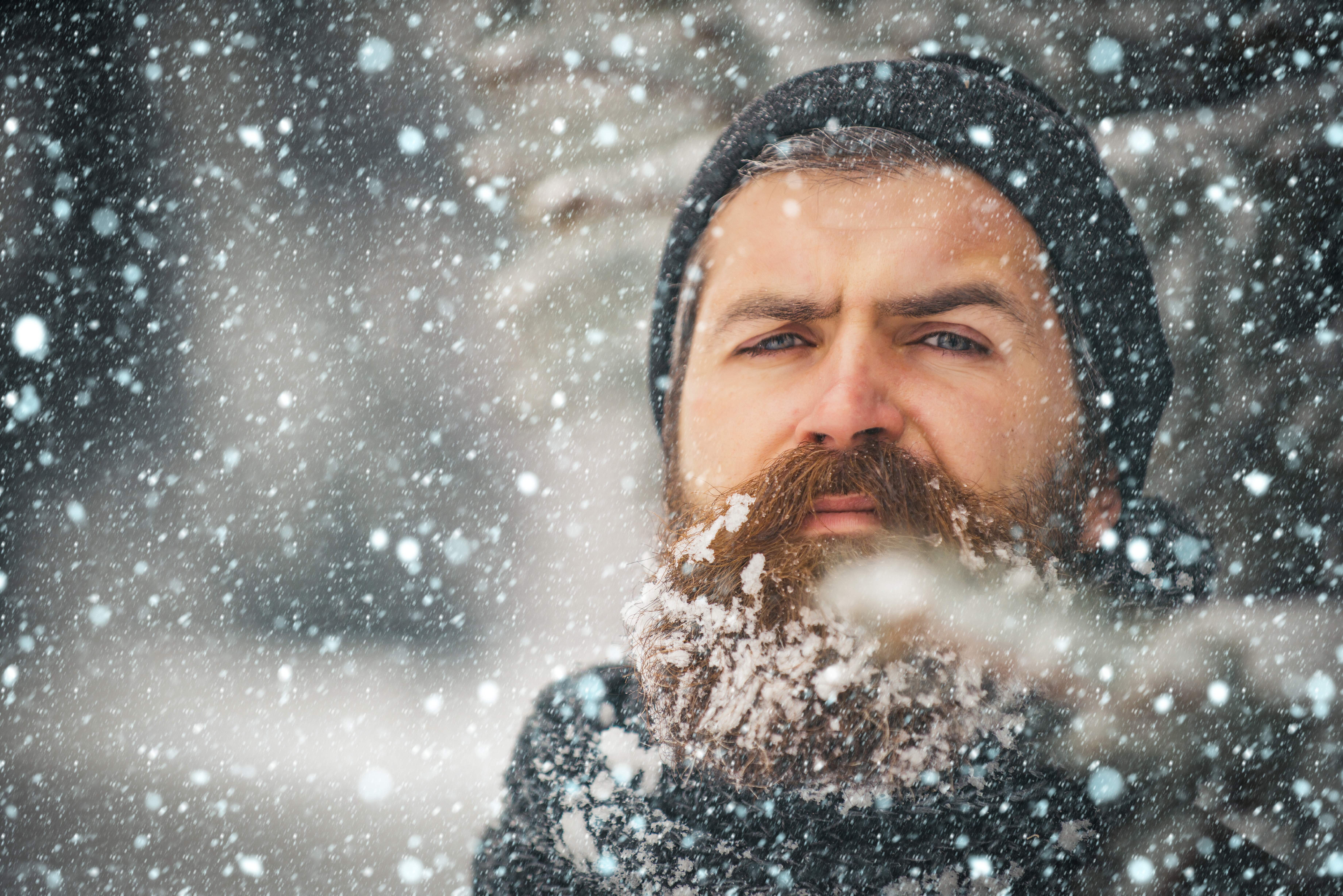 Ein Mann mit Bart und Hut, der draußen steht, während Schnee fällt | Quelle: Shutterstock