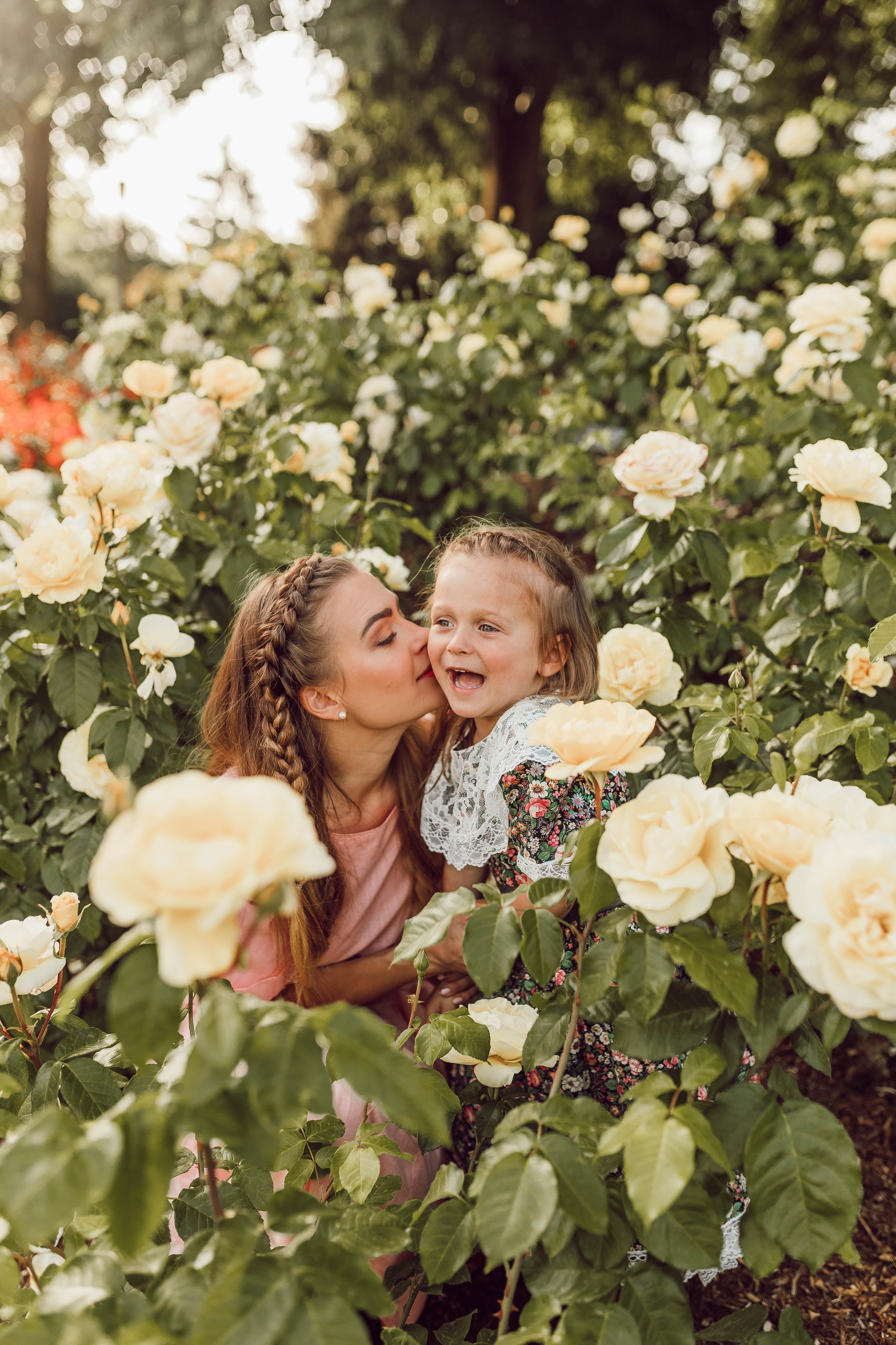 Eine Mutter küsst ihr kleines Mädchen in einem Garten | Quelle: Pexels