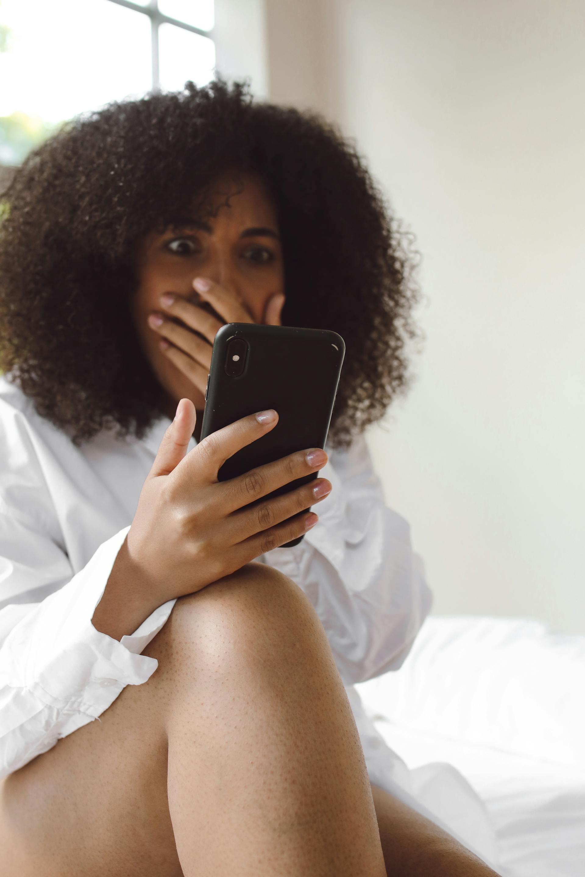 Eine geschockte Frau, die auf ein Telefon schaut | Quelle: Pexels