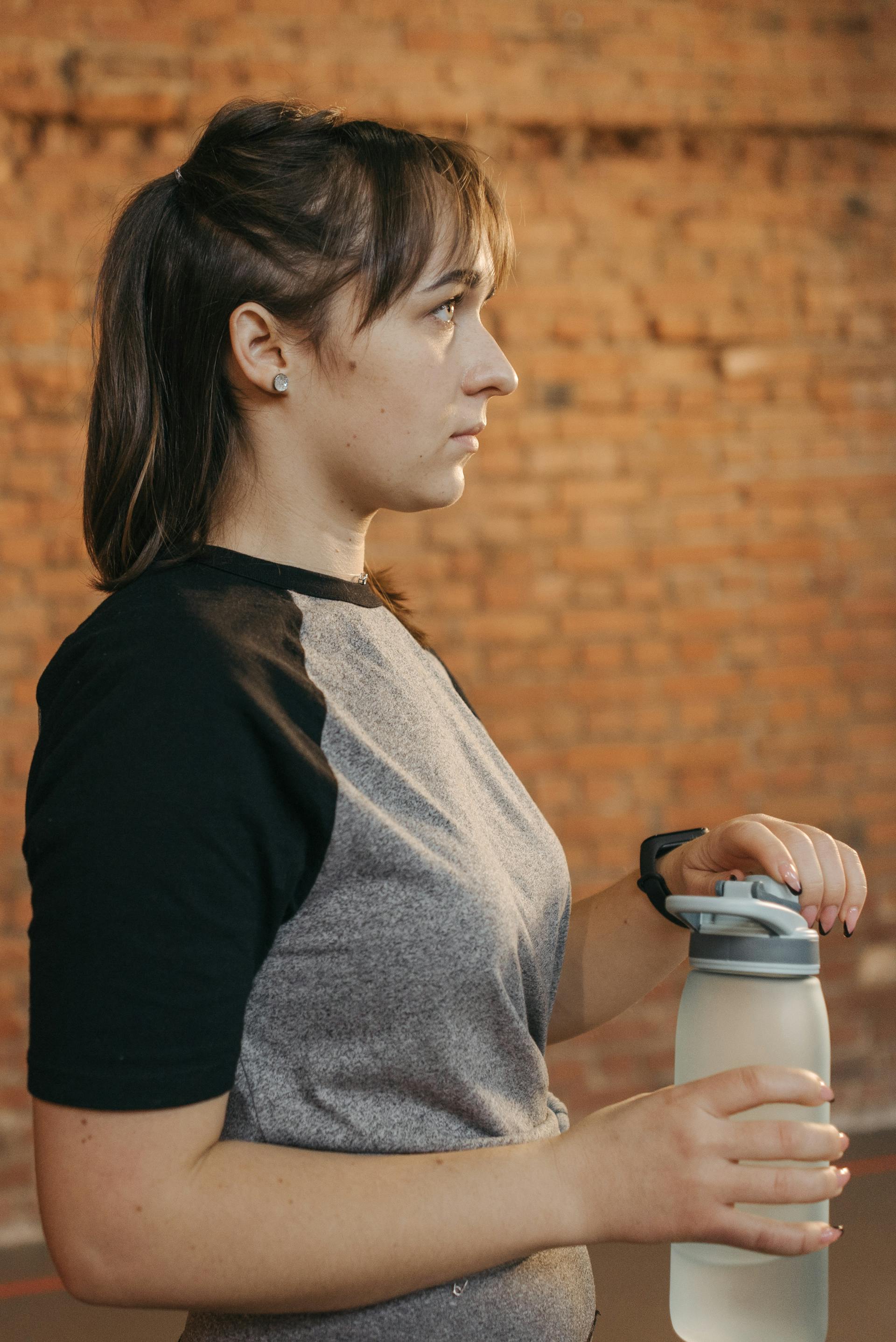 Eine Frau in Trainingskleidung hält eine Wasserflasche | Quelle: Pexels