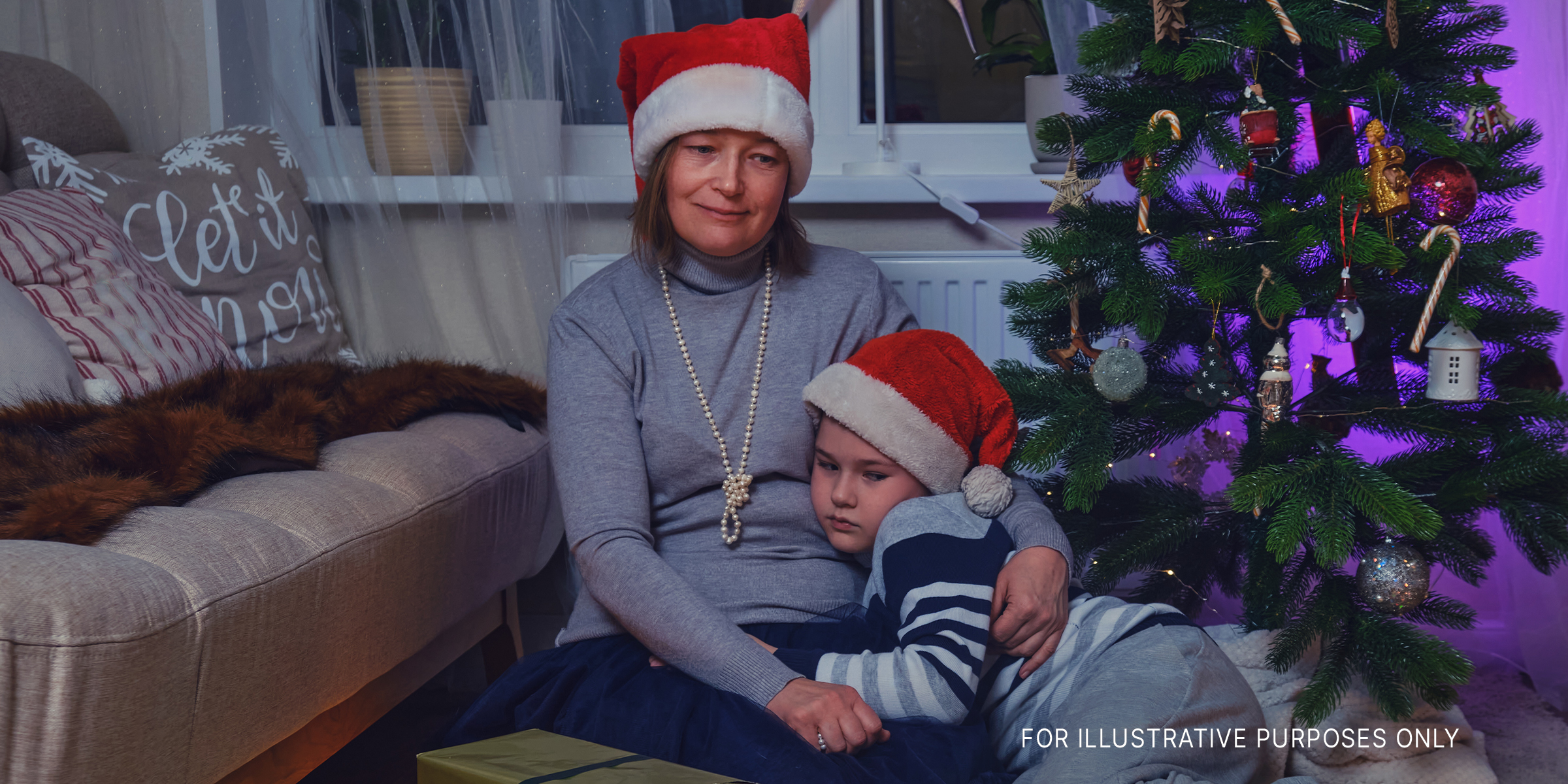 Traurige Mutter und Sohn sitzen neben dem Weihnachtsbaum | Quelle: Getty Images