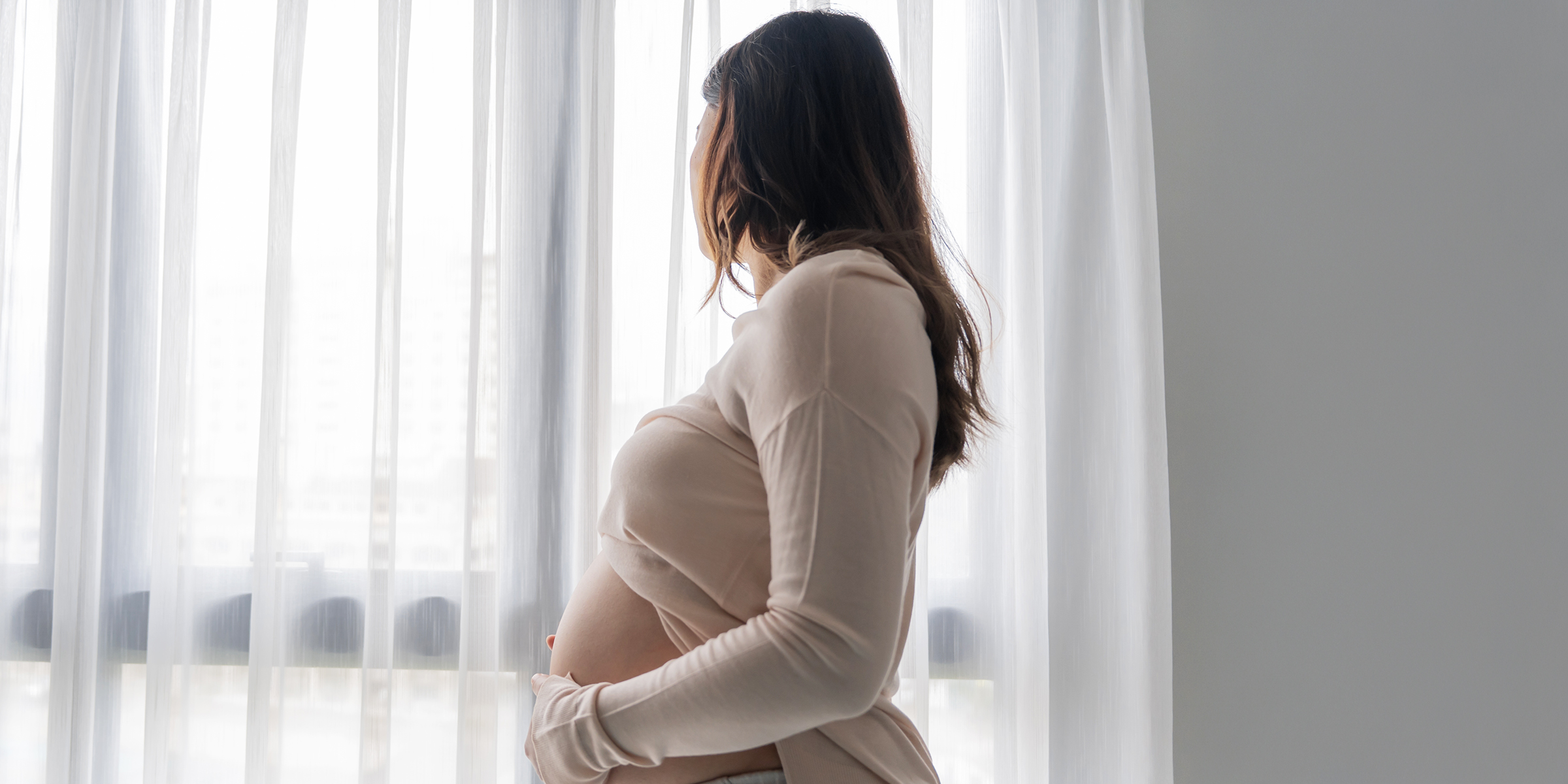 Eine schwangere Frau, die aus einem Fenster schaut | Quelle: Shutterstock