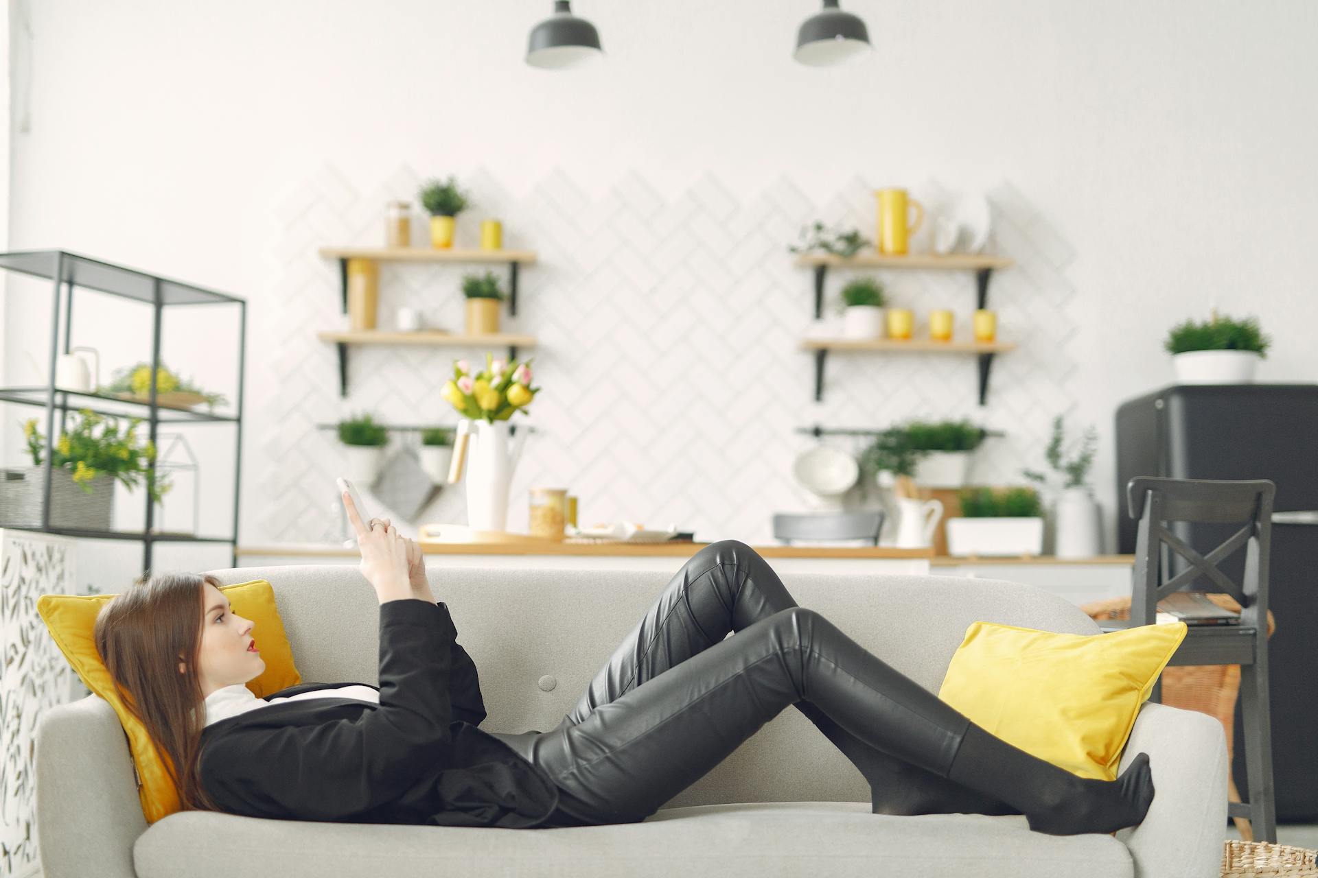 Eine Frau, die auf der Couch liegt und ihr Telefon benutzt | Quelle: Pexels