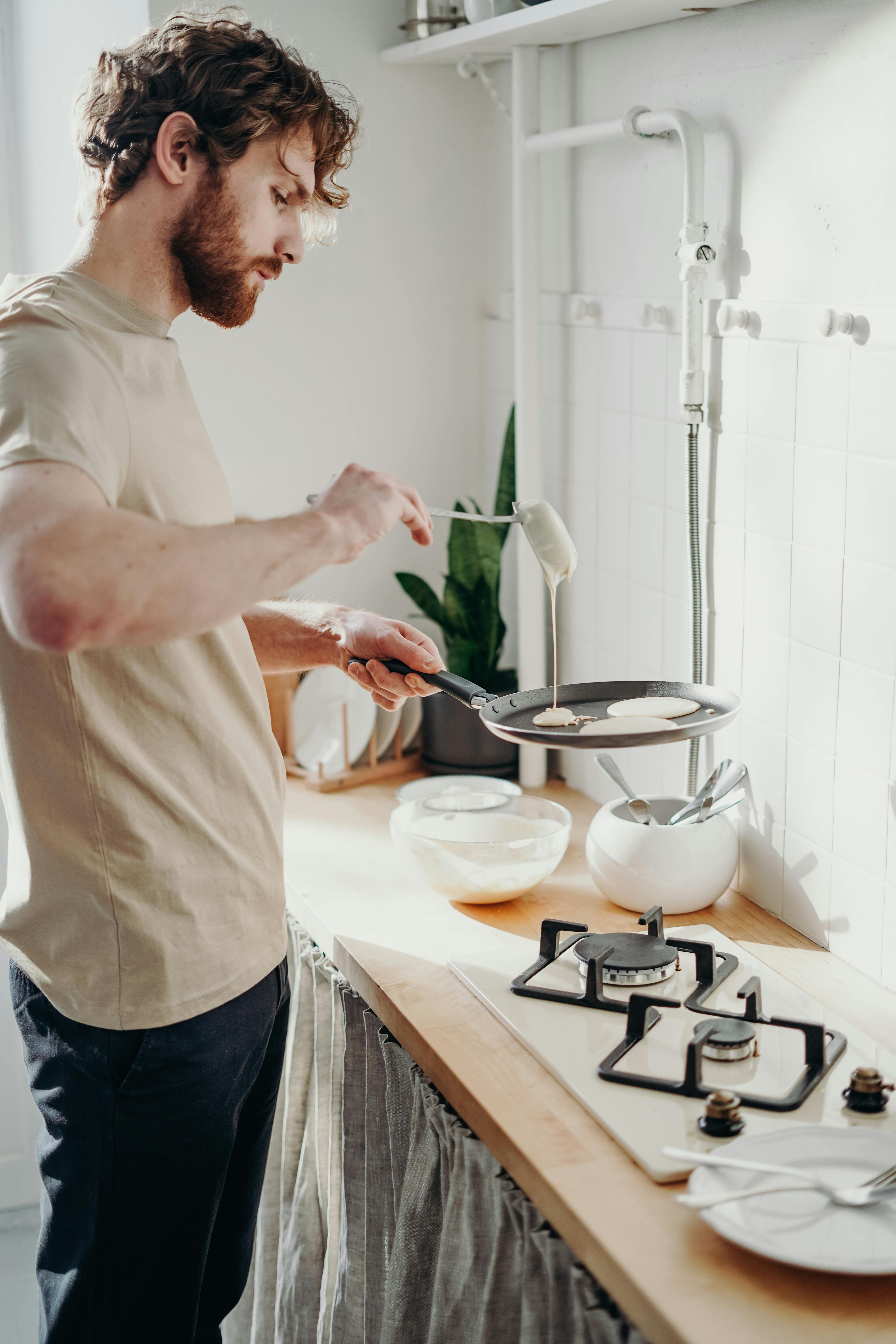 Um homem prepara uma refeição no fogão | Fonte: Pexels