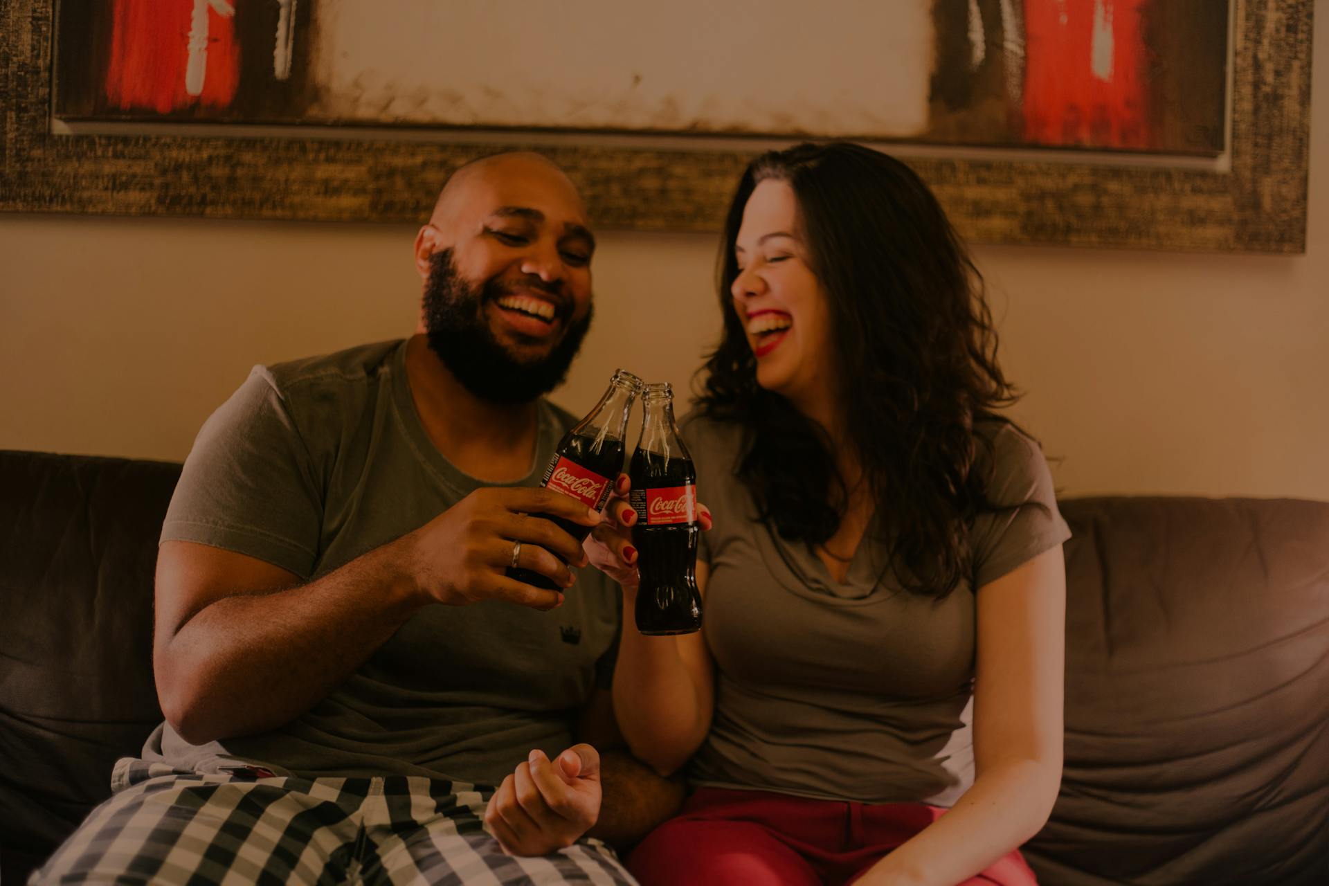 Ein Paar lacht, während es Softdrinkflaschen hält | Quelle: Pexels
