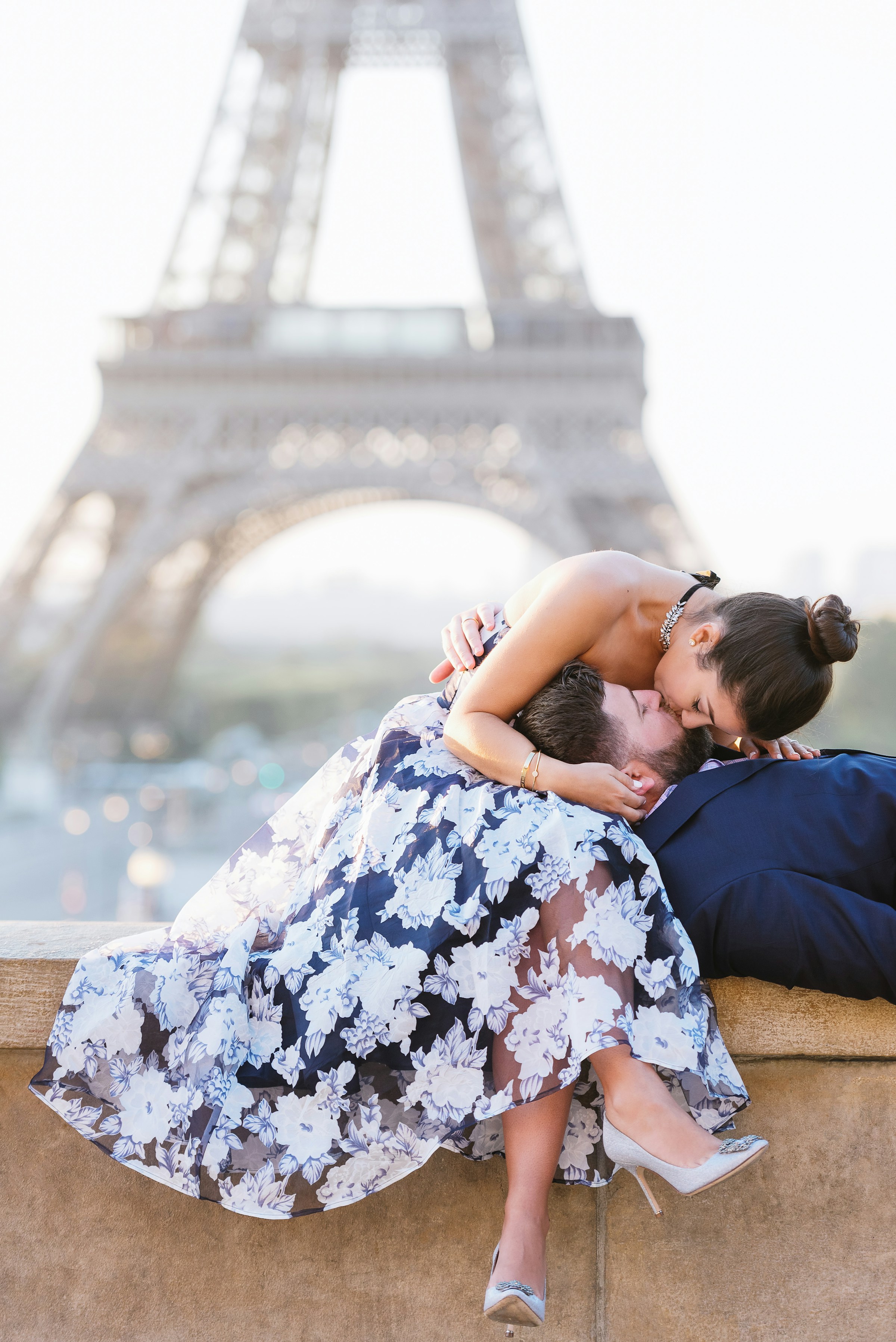 Ein Paar küsst sich auf einem Sims vor dem Eiffelturm in Paris | Quelle: Unsplash