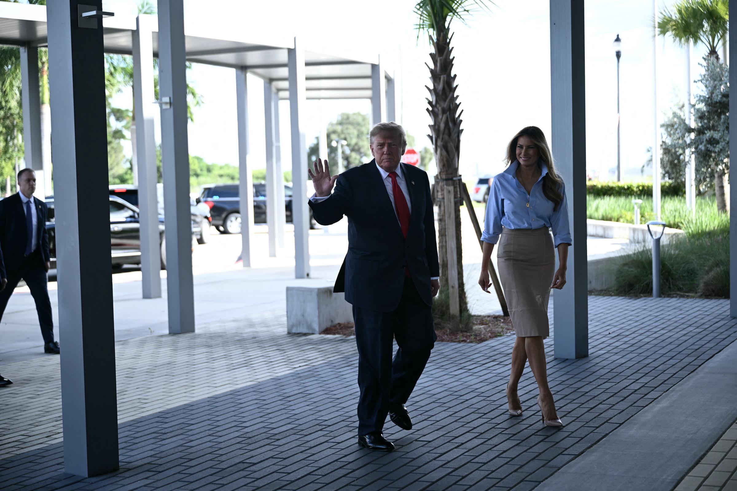 Begleitet von Donald Trump, der den Zuschauern entlang des sonnendurchfluteten Außenkorridors zuwinkt, präsentiert Melania die klaren Linien ihres maßgeschneiderten Outfits und schreitet in hochhackigen, hautfarbenen Pumps mit spitzer Zehenpartie von Christian Louboutin voran, die den unterhalb des Knies endenden Saum mit einem messerscharfen Schwung abrunden.
