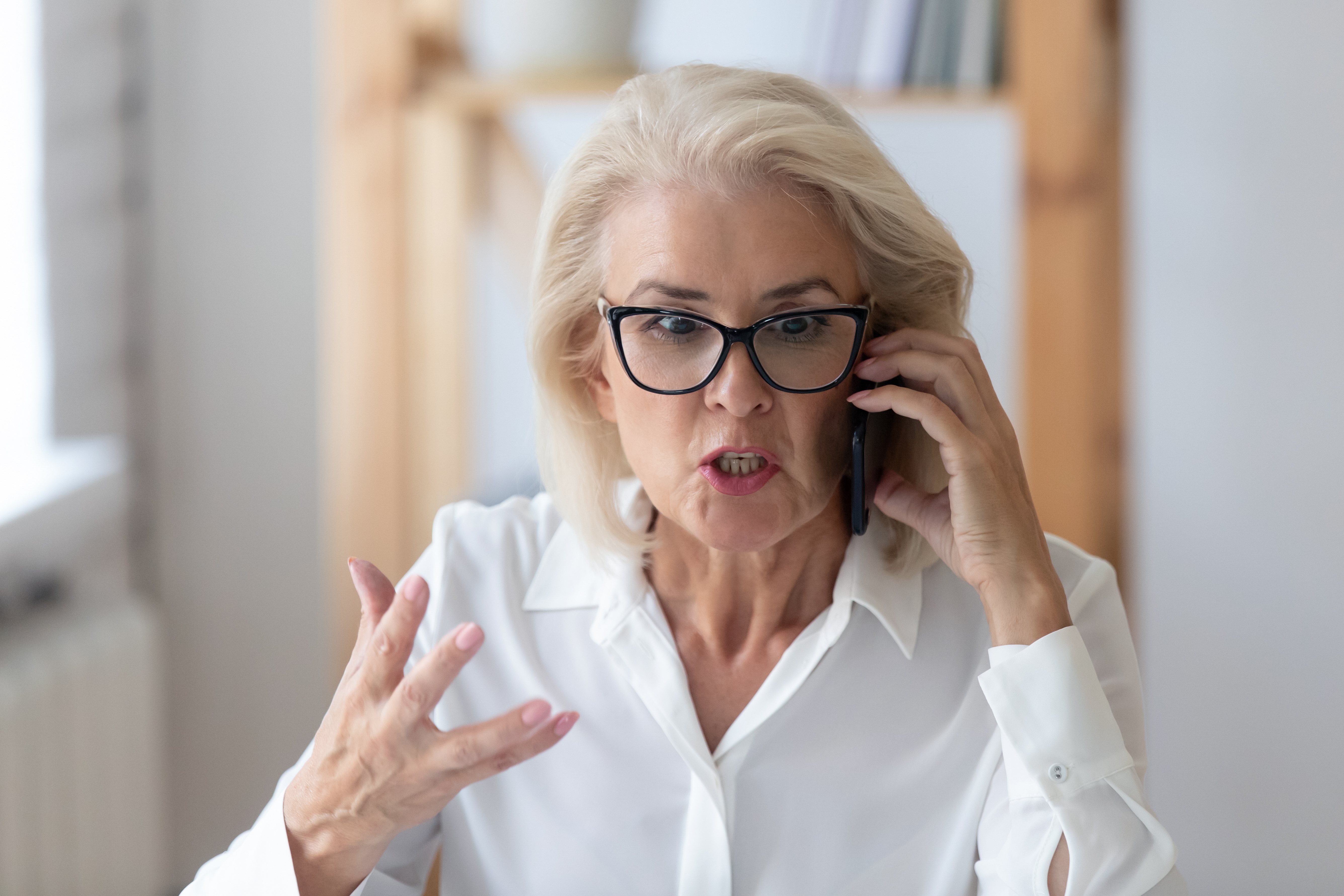 Eine empörte ältere Frau beim Telefonieren | Quelle: Shutterstock