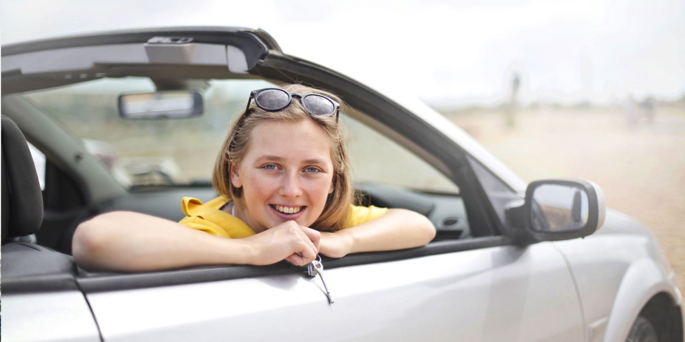 Eine junge Frau lächelt fröhlich, während sie sich aus einem Cabrio lehnt | Quelle: Pexels