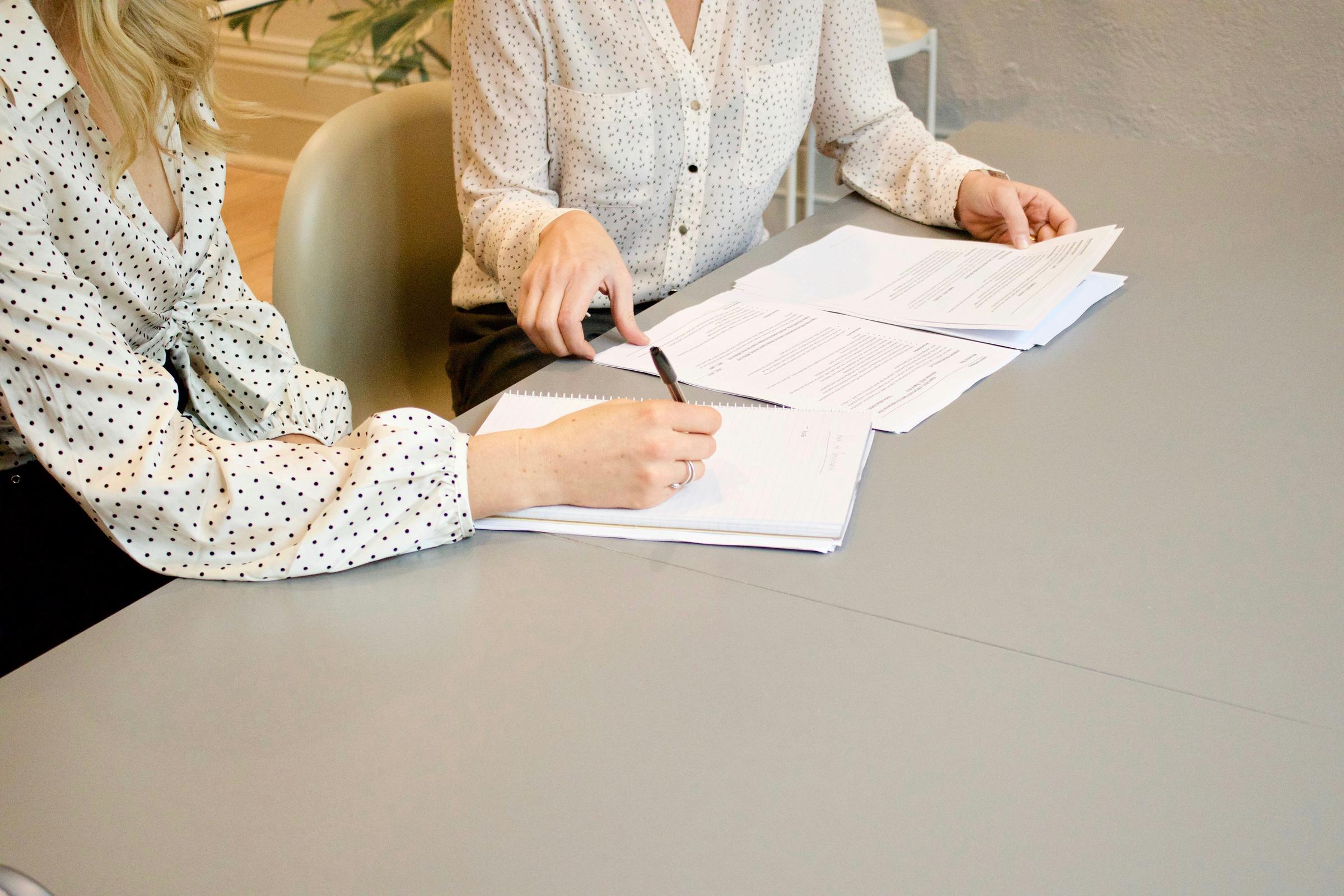 Zwei Frauen sitzen an einem Tisch mit Papierkram | Quelle: Unsplash