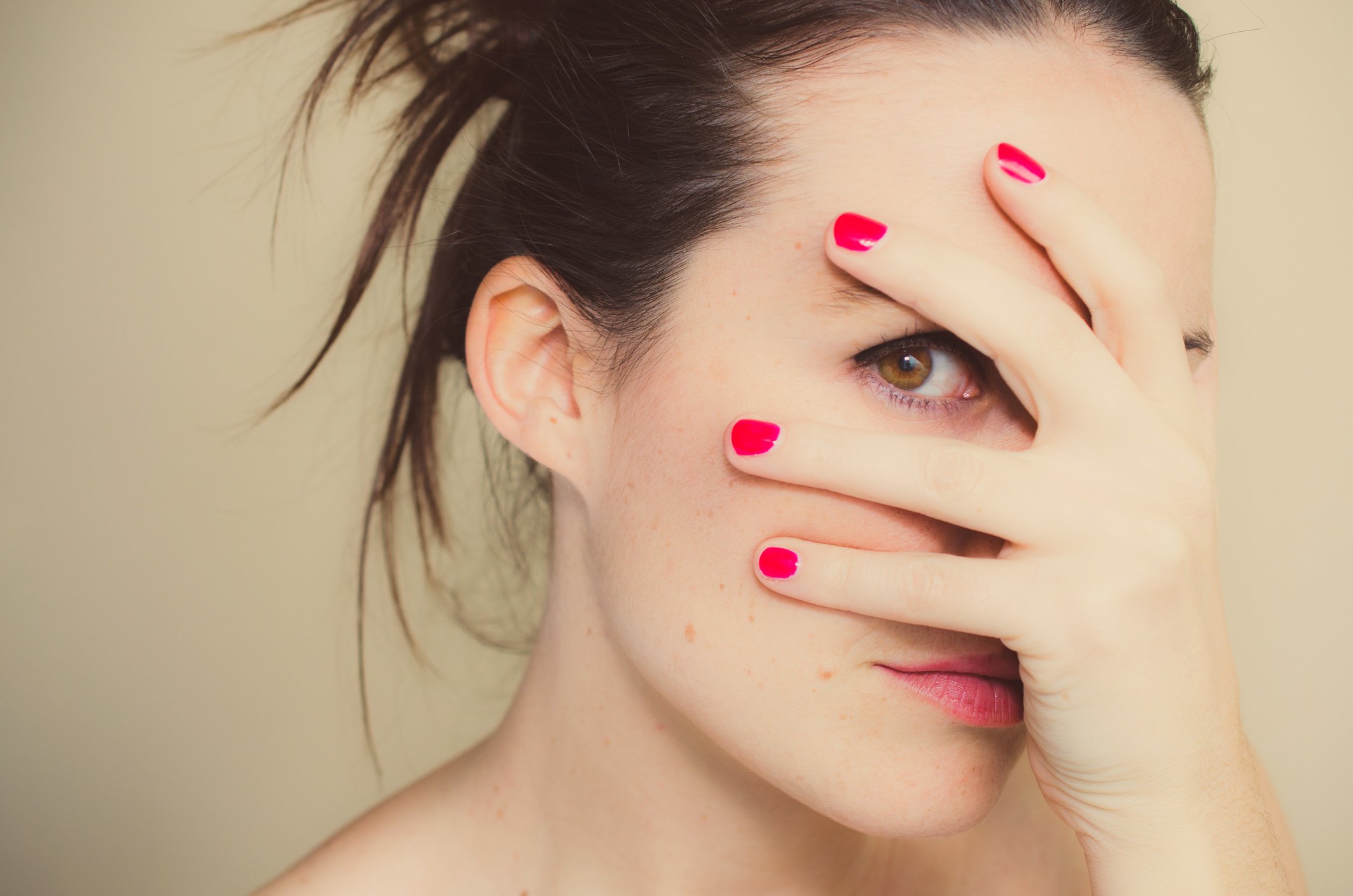 Geheimnisvolles Mädchen mit roten Nägeln und Hand auf Gesicht. I Quelle: Getty Images