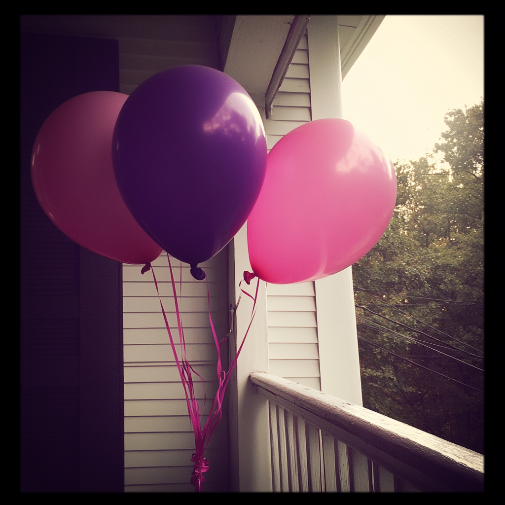Rosa und lila Luftballons auf einer Veranda | Quelle: Midjourney