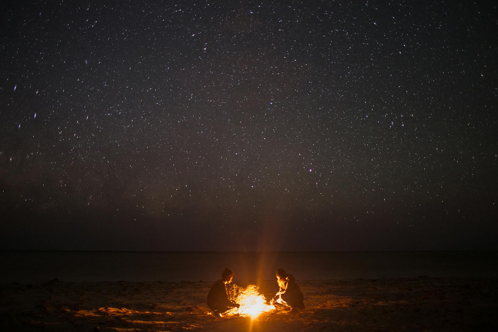 Menschen bei einem nächtlichen Lagerfeuer am Strand | Quelle: Pexels