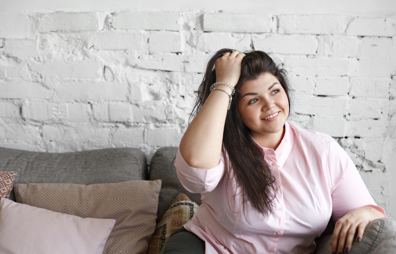 Eine Frau, die auf der Couch sitzt und selbstbewusst posiert | Quelle: Freepik