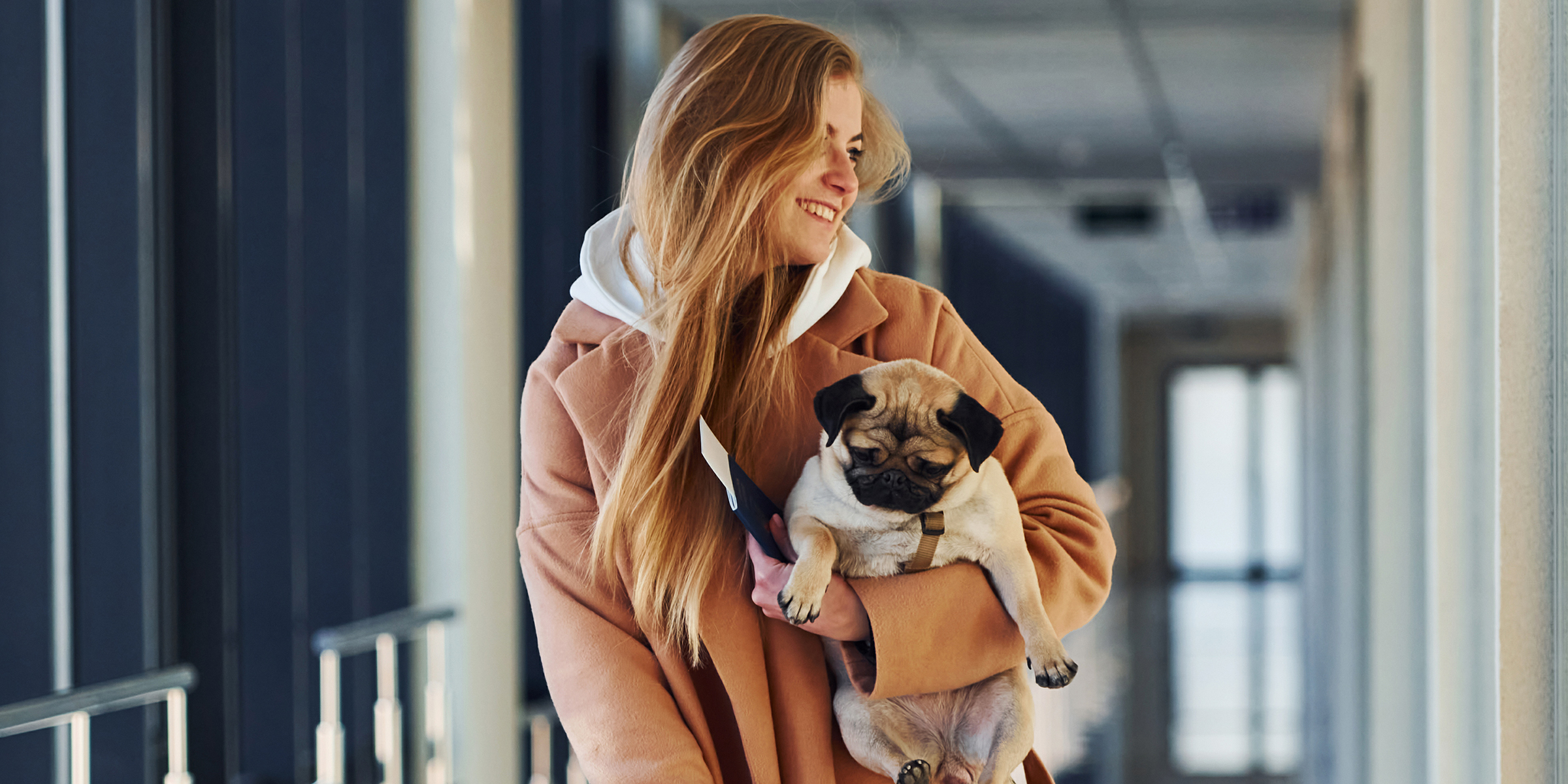 Eine lächelnde Frau mit einem kleinen Hund | Quelle: Shutterstock