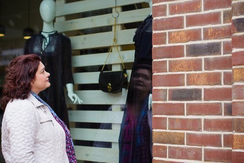 Frau schaut sich Auslade an im Schaufenster | Quelle: Shutterstock