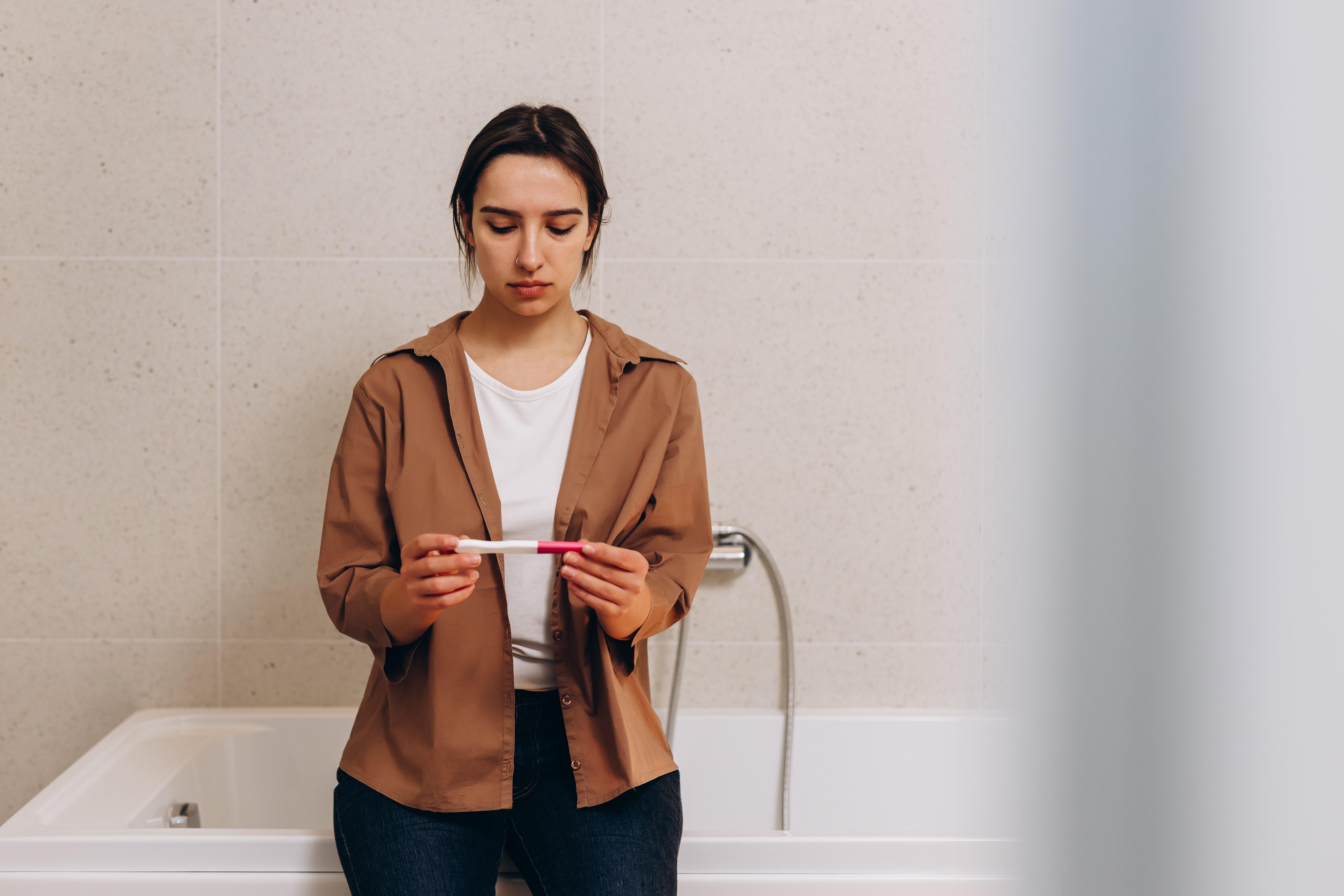 Eine junge Frau schaut sich einen Schwangerschaftstest an | Quelle: Shutterstock