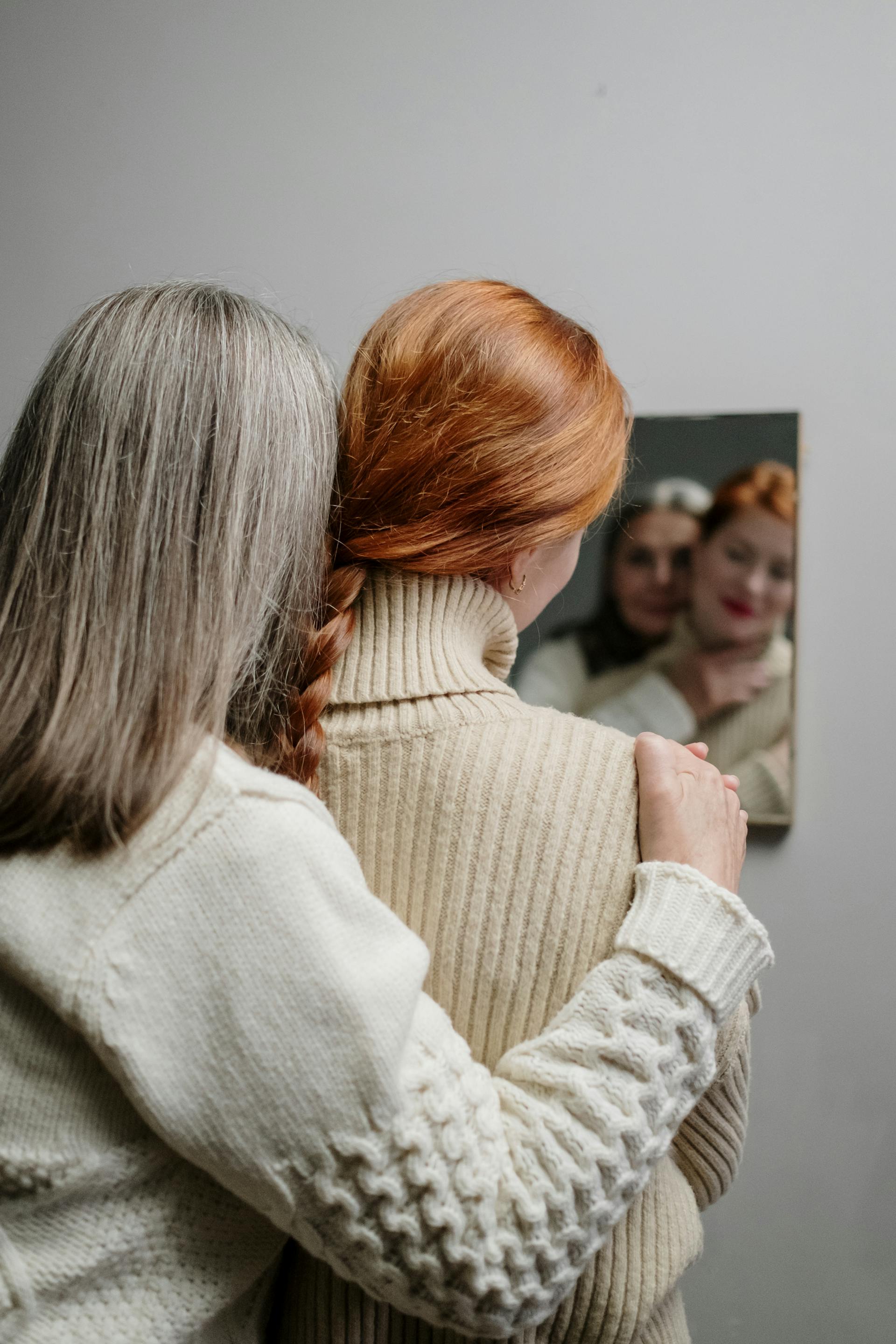 Eine Mutter und ihre Tochter umarmen sich, während sie ihr Spiegelbild betrachten | Quelle: Pexels