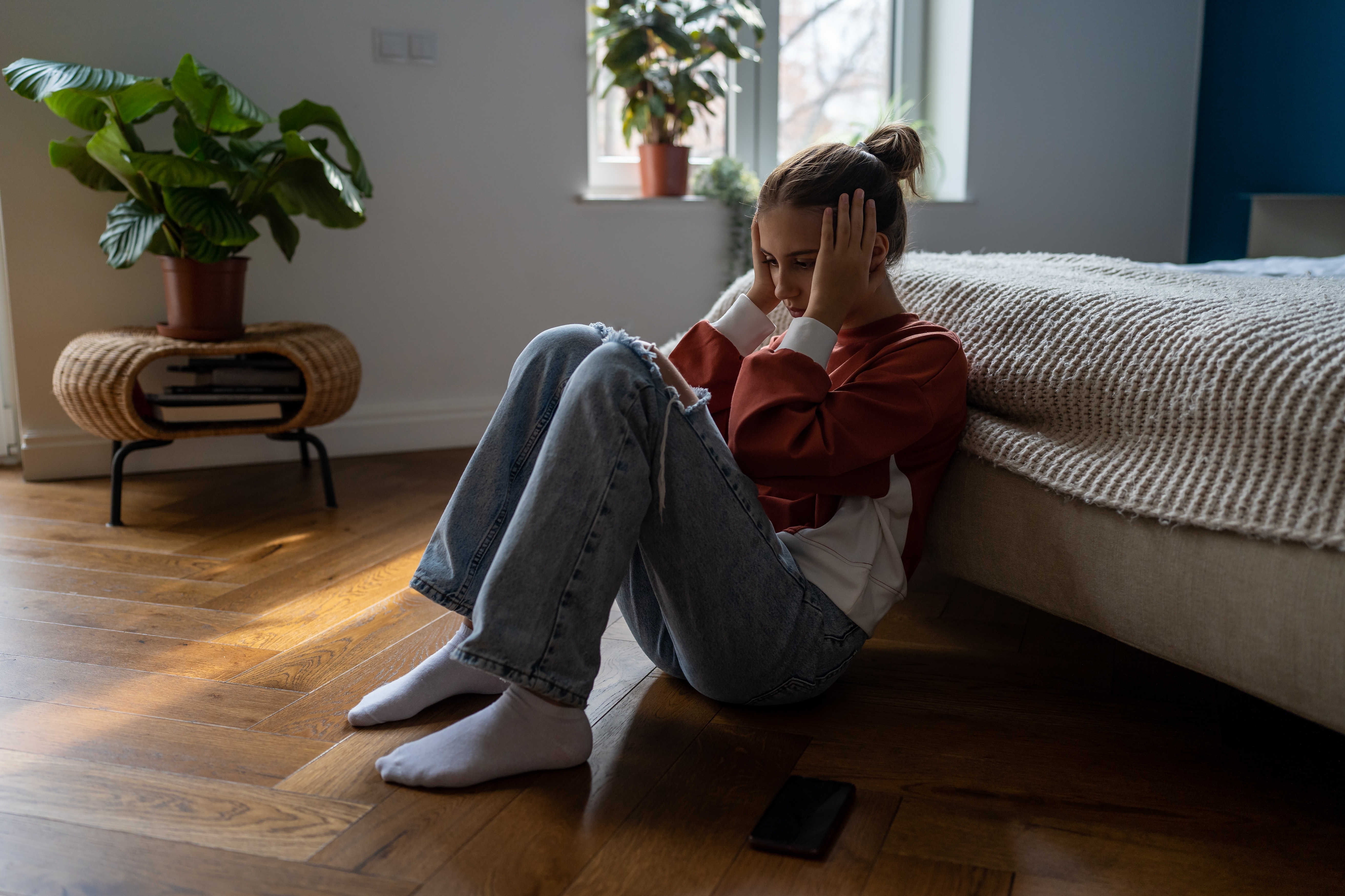 Ein frustriertes Teenager-Mädchen sitzt auf dem Boden | Quelle: Shutterstock