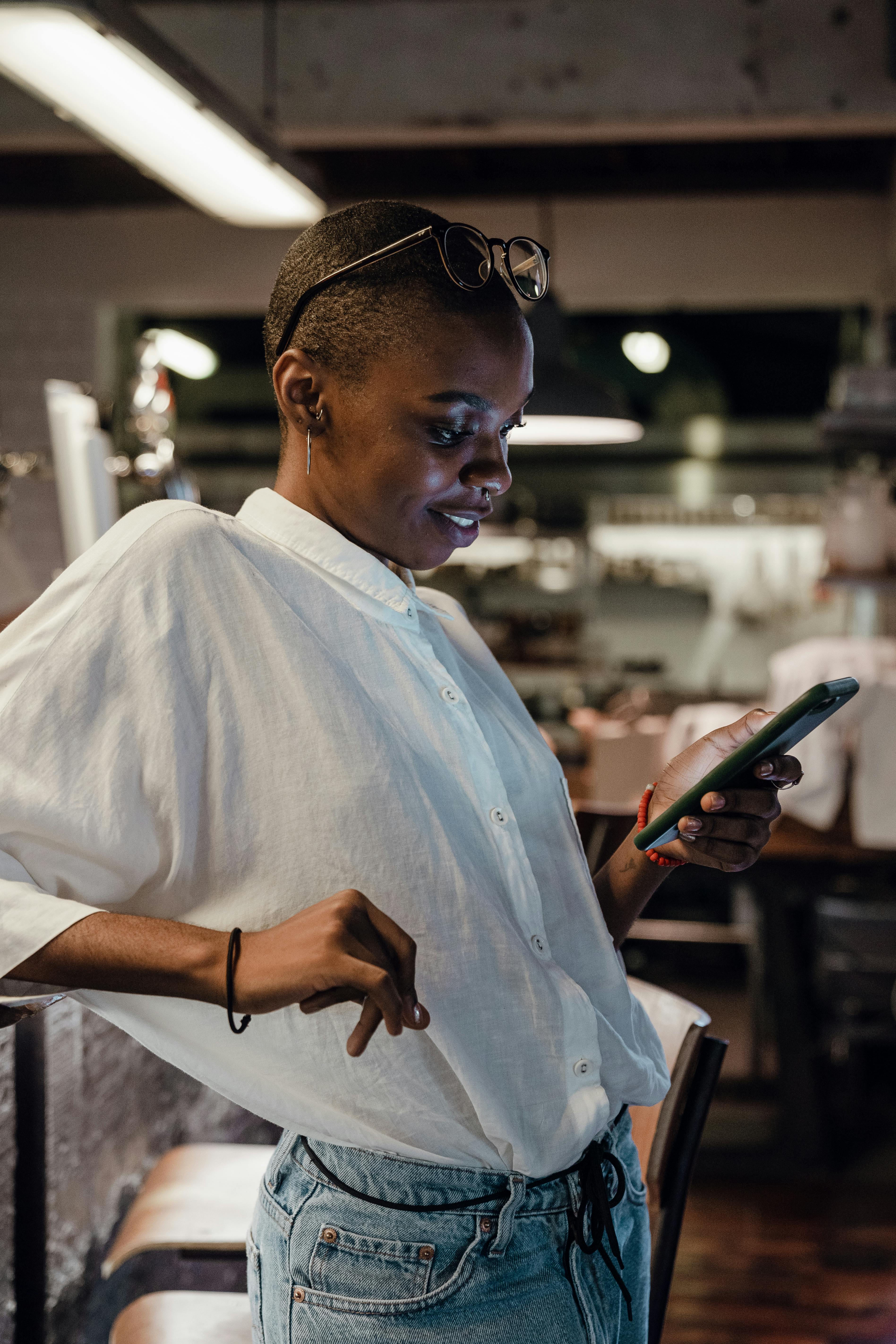 Eine glückliche Frau, die in einem Café auf ihr Telefon schaut | Quelle: Pexels